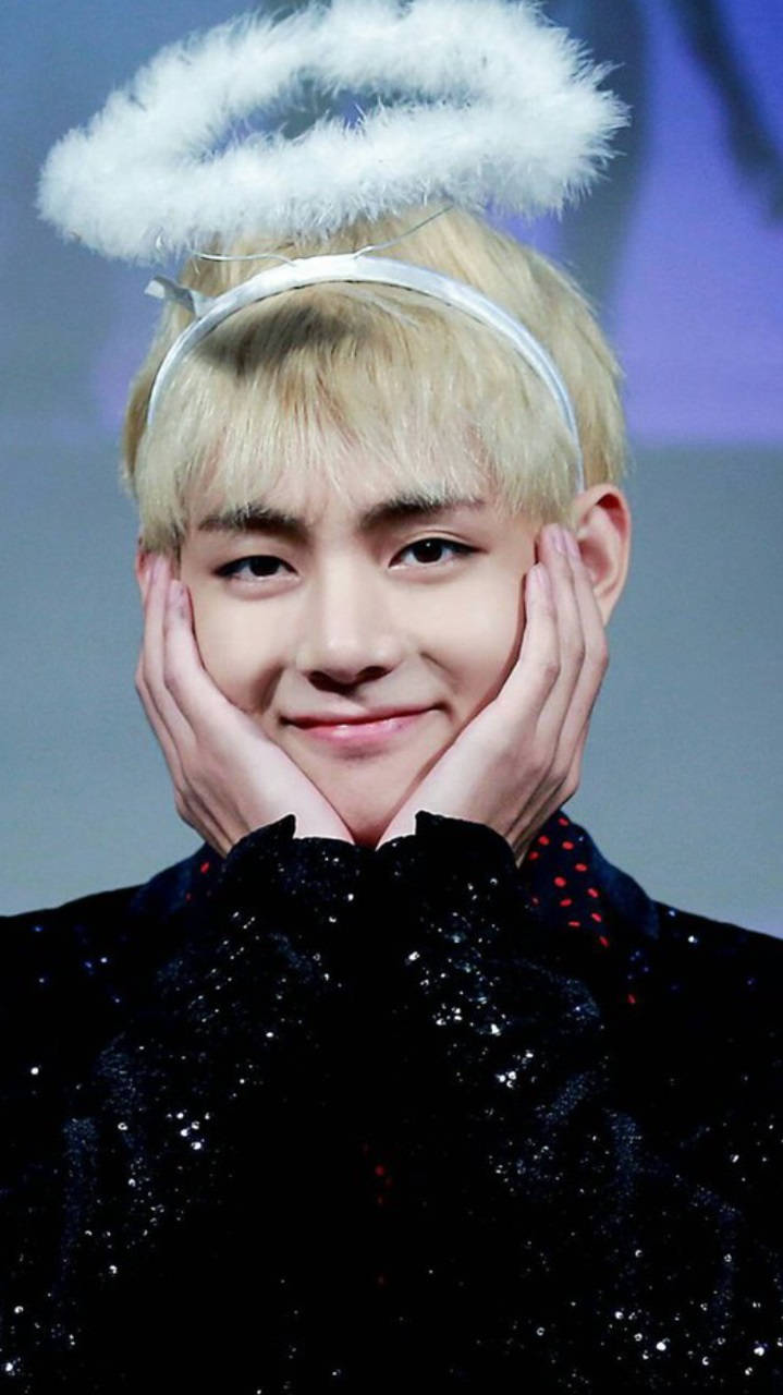 Cute Bts 桌布 壁紙 — 一位金髮年輕男子，帶著蓬鬆的白色光環，雙手捧著臉頰溫柔微笑。