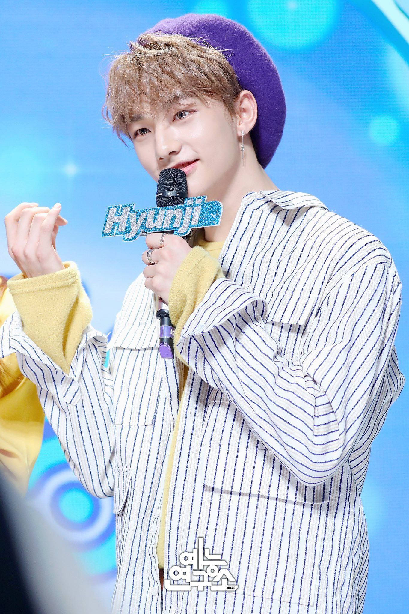 Stray Kids 桌布 壁紙 — 一位金髮年輕男子戴著紫色貝雷帽和條紋襯衫，在明亮的藍色舞台上拿著麥克風。