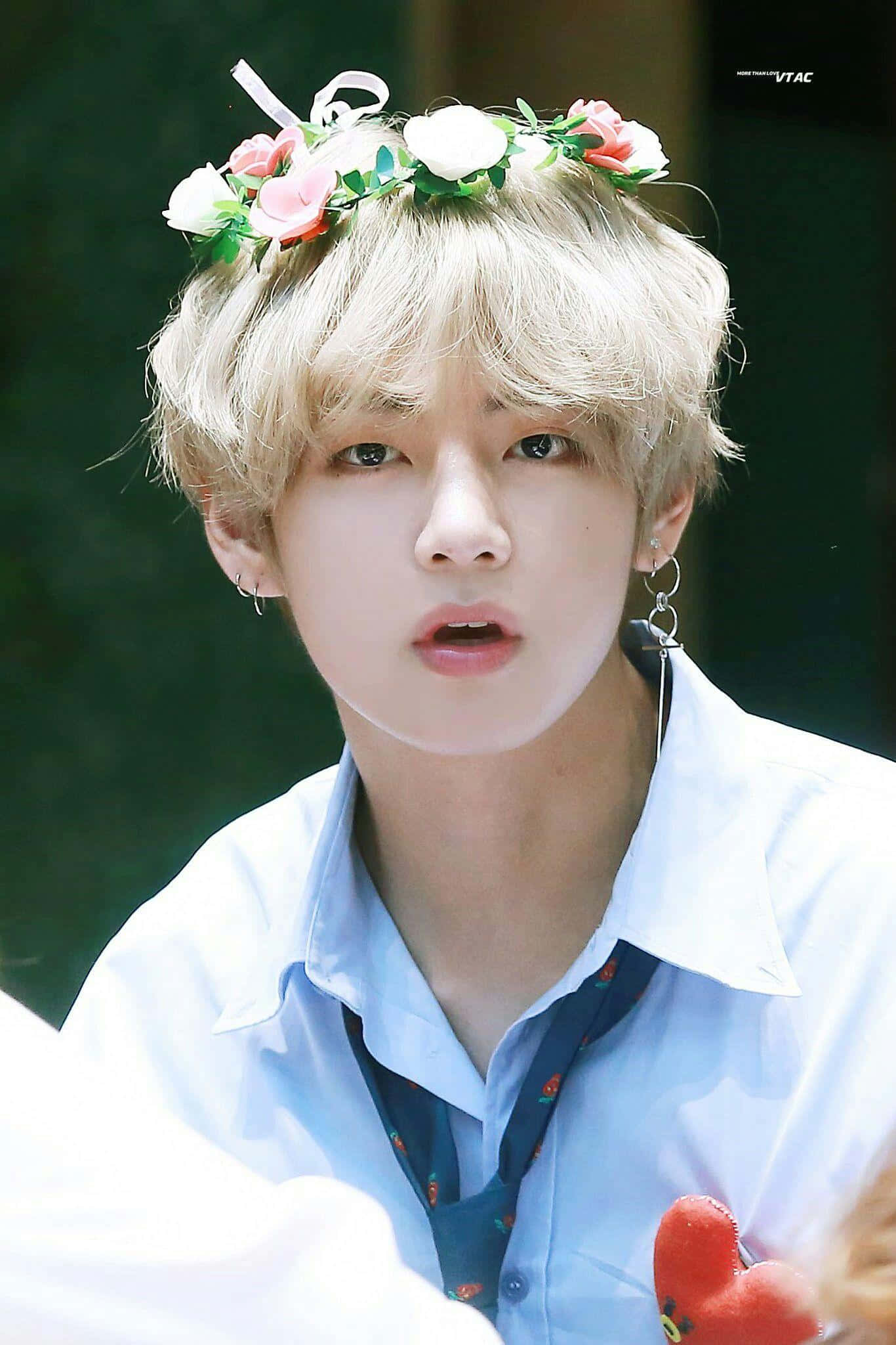 Taehyung Cute 桌布 壁紙 — 一位金髮年輕男子戴著花冠，穿著淺藍色襯衫，在明亮的日光下戶外。
