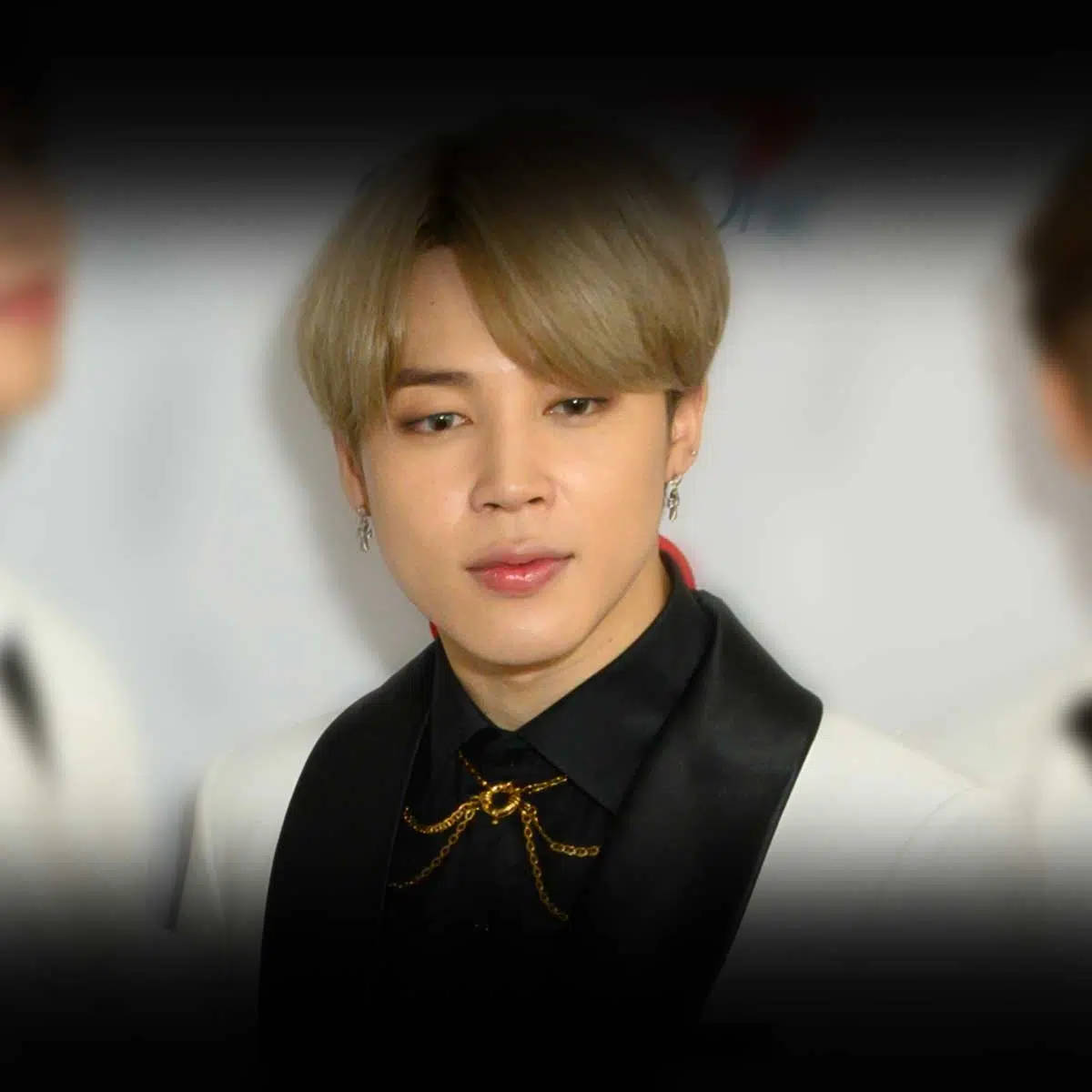 BTS 智旻 桌布 壁紙 — 一位金髮年輕男子穿著黑色背心和金鏈配飾，在模糊背景下的特寫肖像。