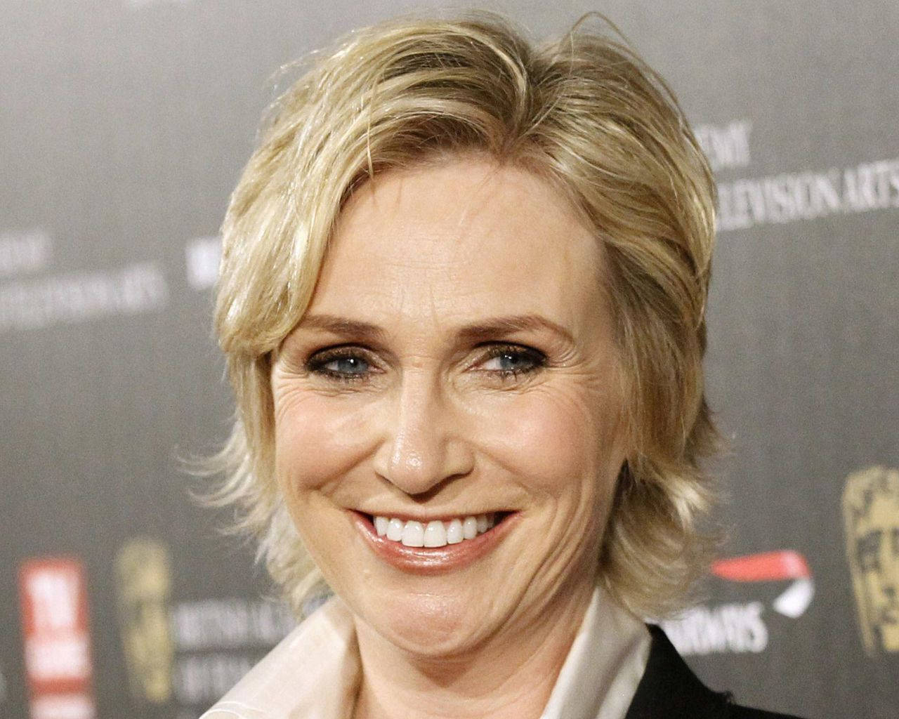 Celebrity 桌布 壁紙 — 一位金髮微笑女士在紅地毯活動中的特寫肖像，背後有模糊的獎項標誌。