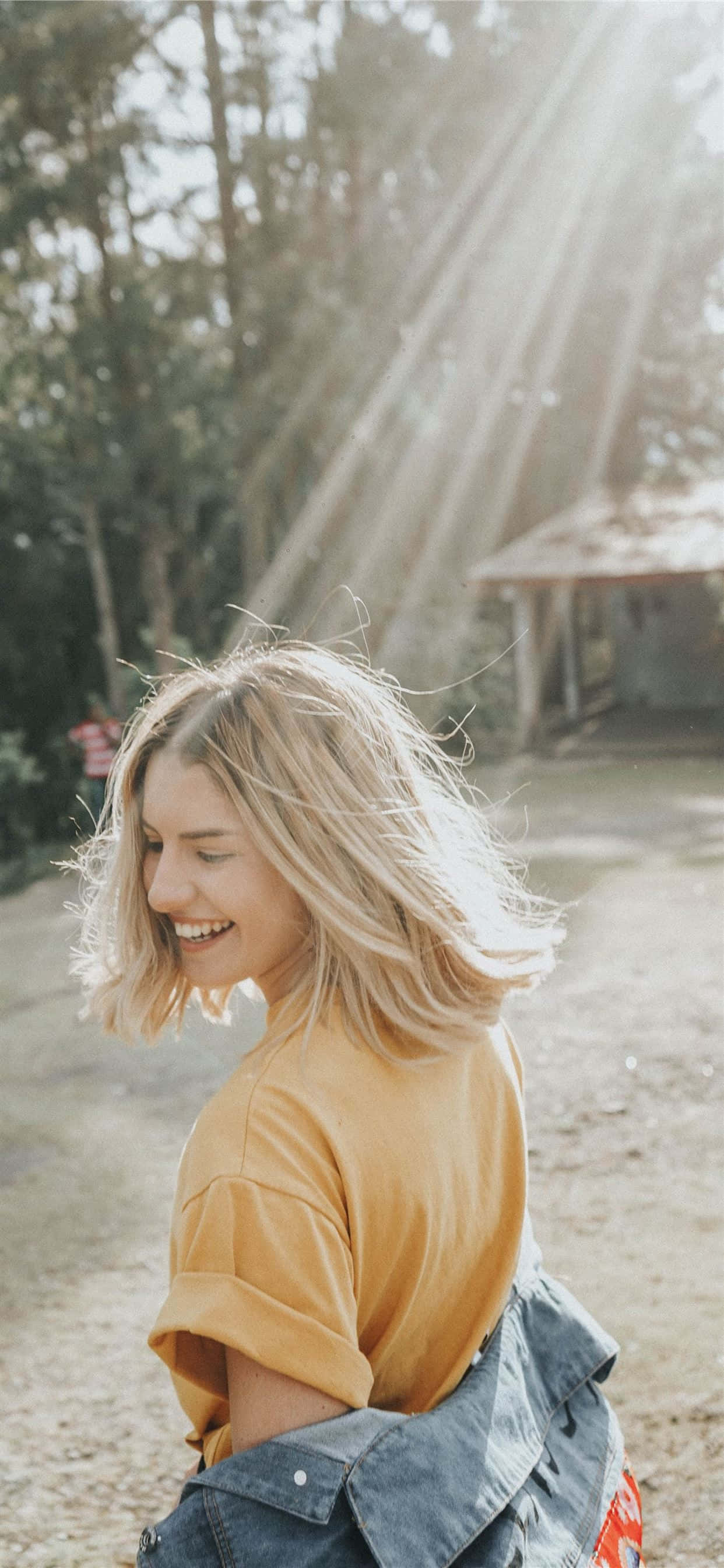 Beautiful Girl 桌布 壁紙 — 一位金髮微笑的女性站在戶外，金色的陽光穿過她身後的樹木照射進來。