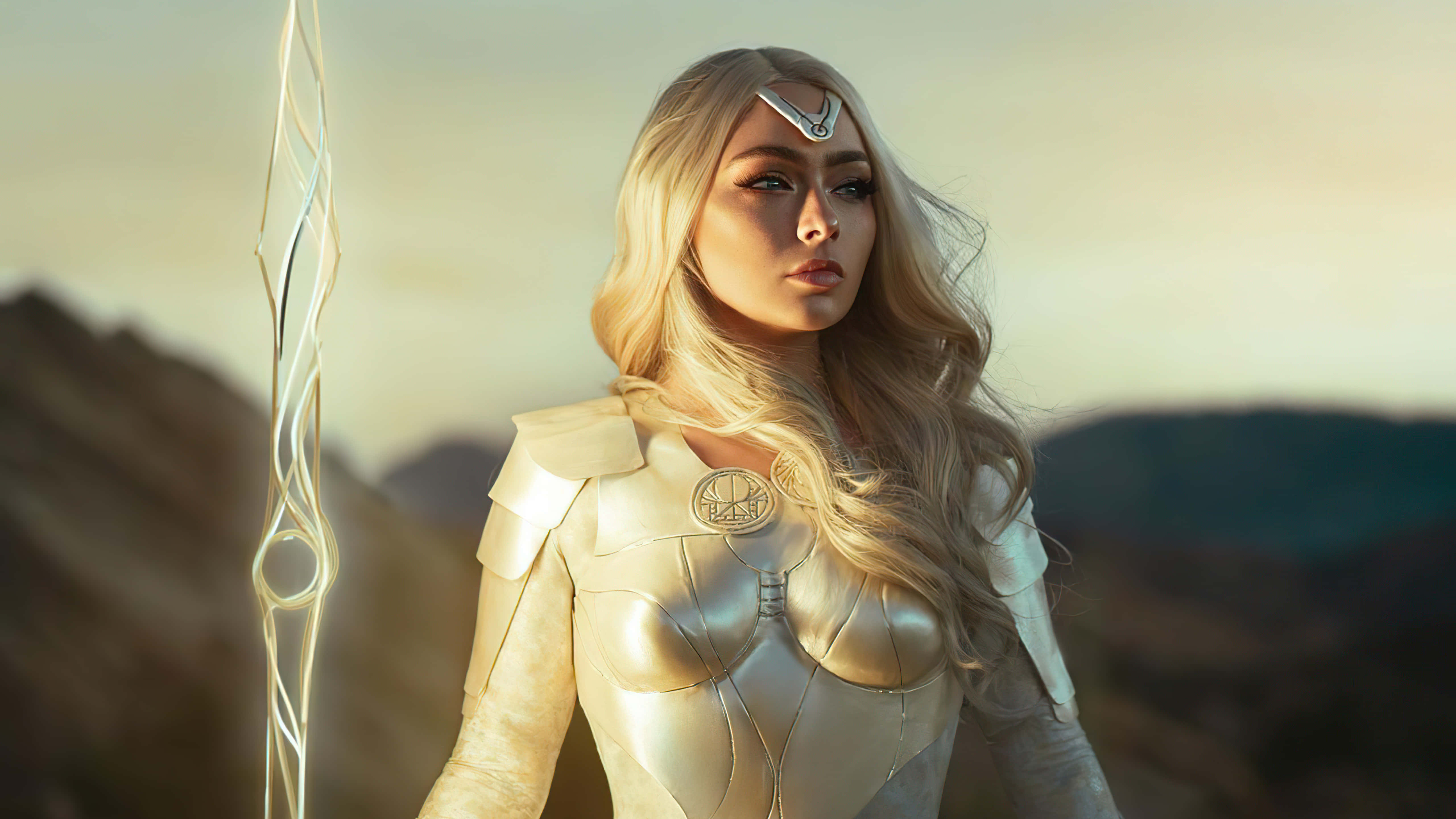cosplay 桌布 壁紙 — 一位金髮戰士身穿金色盔甲，在金色時刻手持發光法杖，以朦朧的山脈為背景，蓄勢待發。