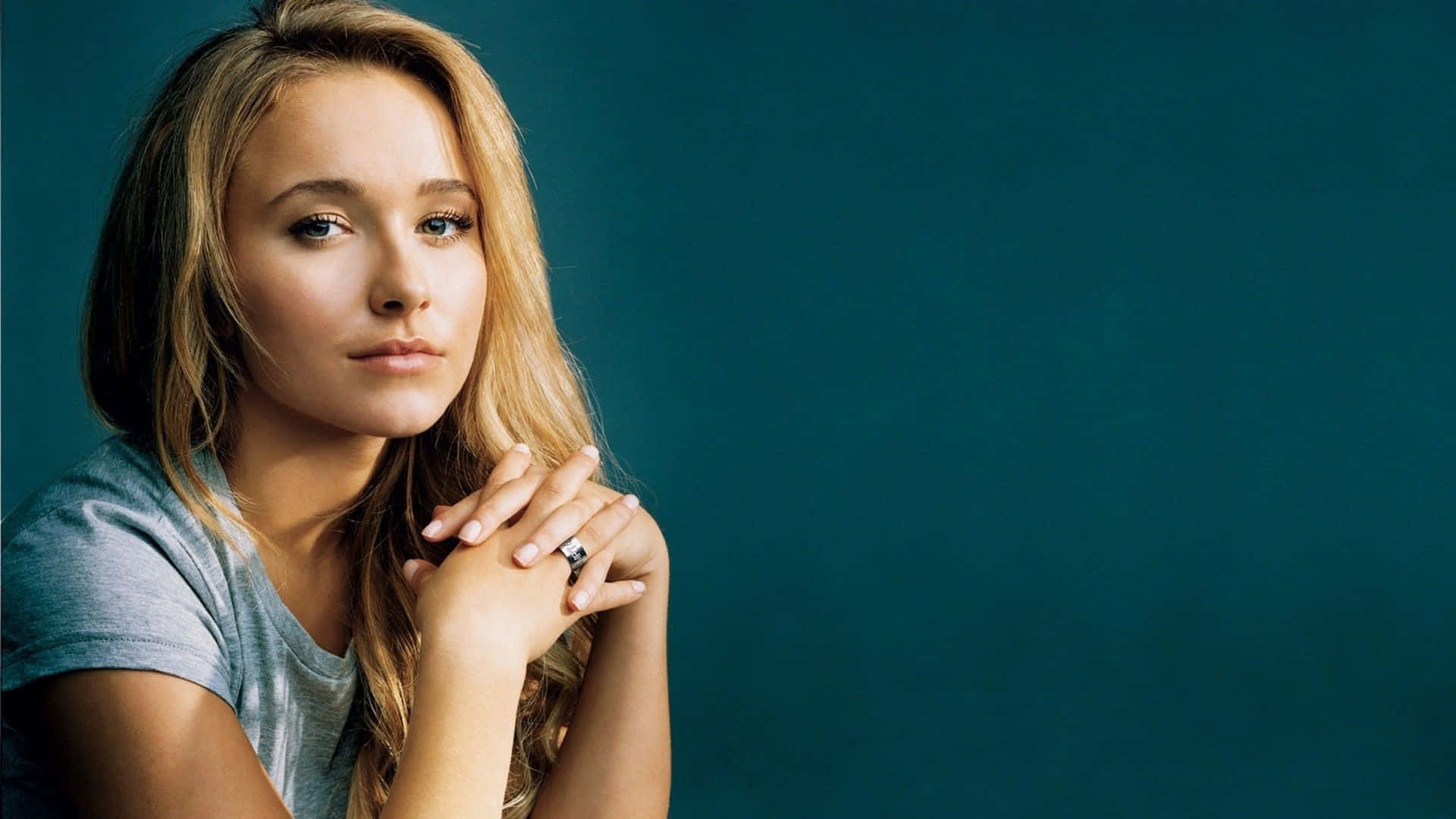 hayden panettiere 桌布 壁紙 — 一位金髮戴戒指的年輕女性，在純色青綠色背景前若有所思地凝視。