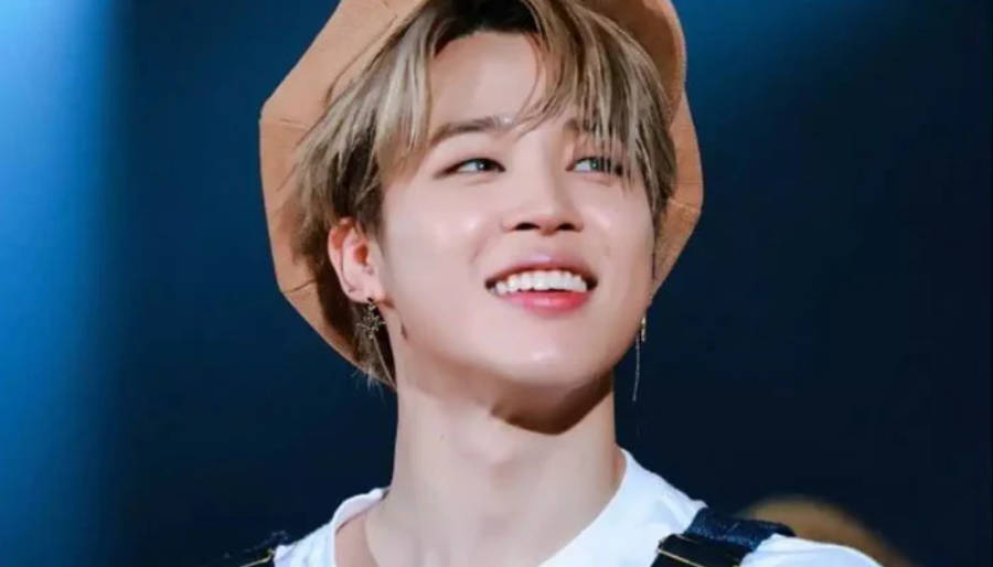 BTS 智旻 桌布 壁紙 — 一位金髮戴著棕色帽子的年輕男子在深藍色背景上洋溢著喜悅。