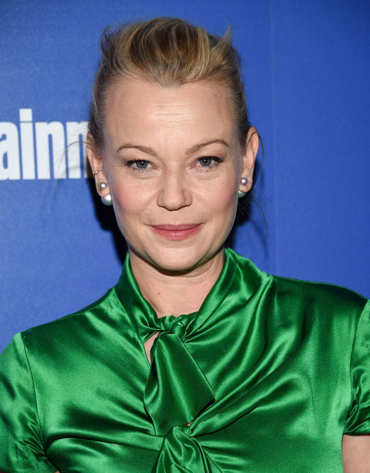 Actress HD 桌布 壁紙 — 一位金髮整齊盤起的女士，身穿鮮綠色緞面襯衫，領口繫有蝴蝶結，背景為藍色。