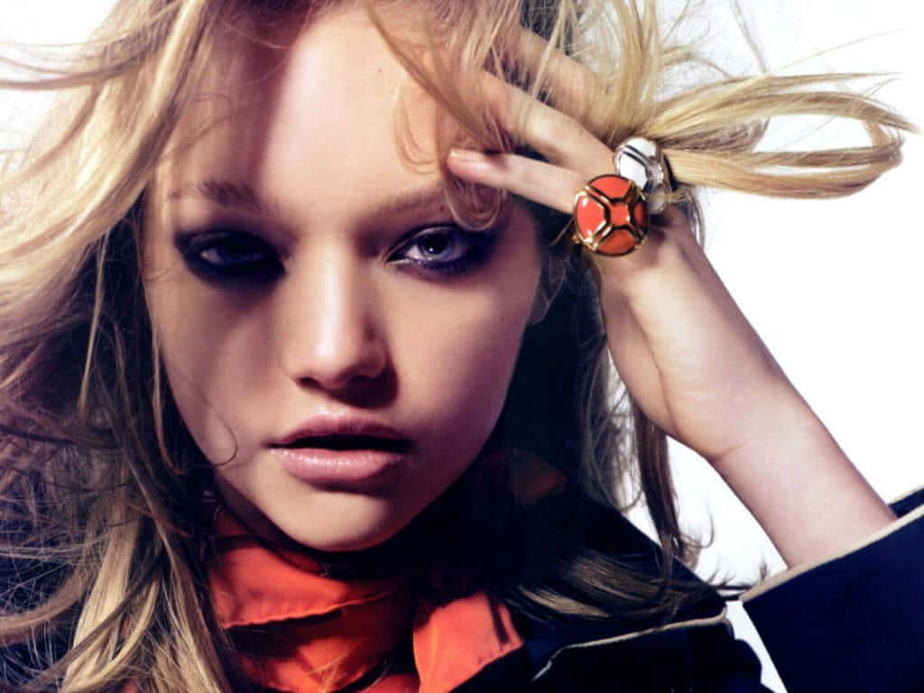 Gemma Ward 桌布 壁紙 — 一位金髮模特兒帶著煙燻眼妝和搶眼的橙色戒指，在純白背景前凝視鏡頭。