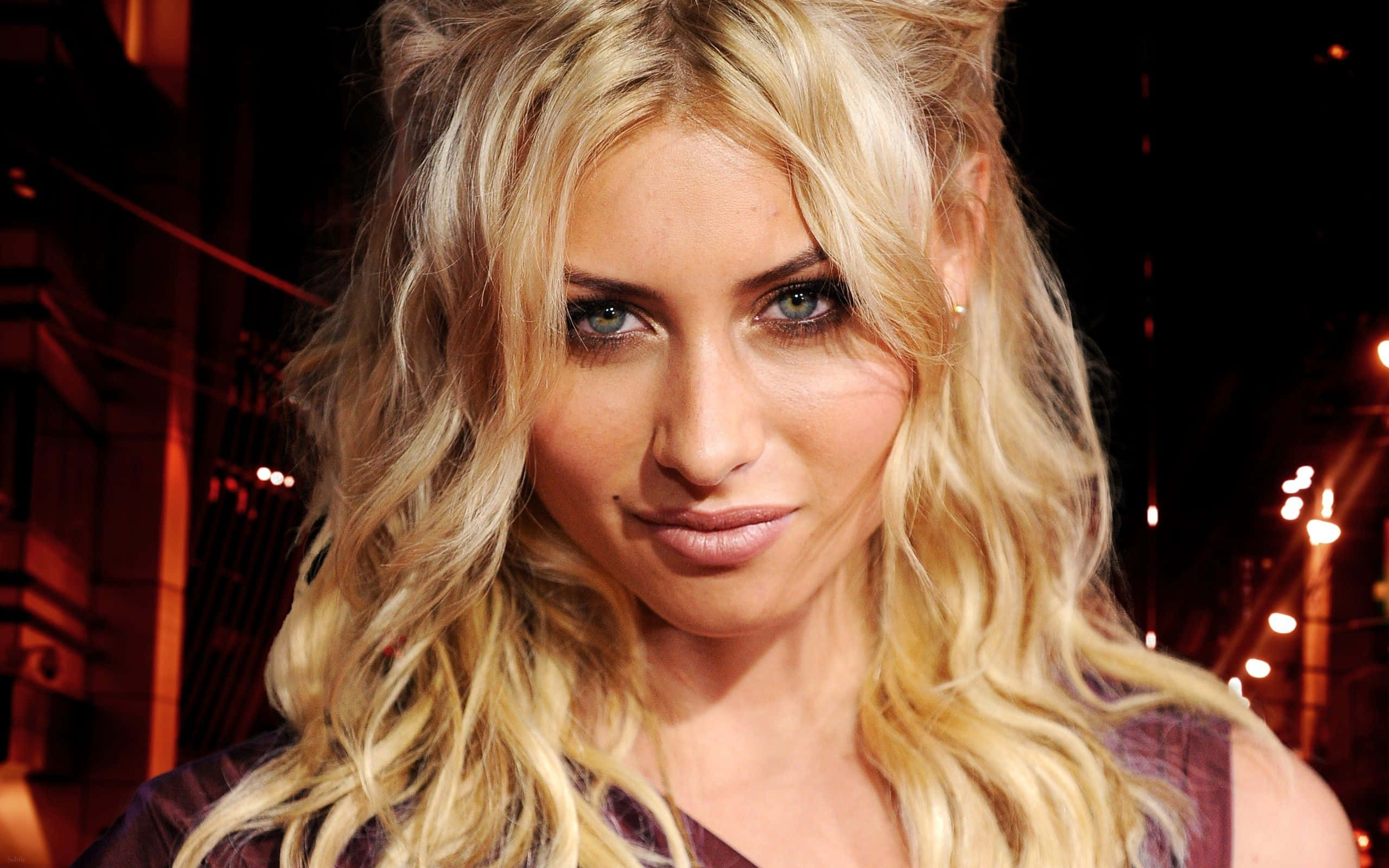 aly michalka 桌布 壁紙 — 一位金髮波浪長髮的女性在溫暖的夜間城市燈光下直視鏡頭。