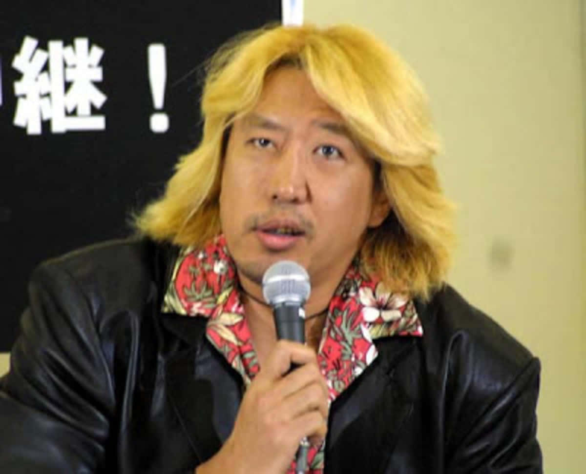 花卉 桌布 壁紙 — 一位金髮男子穿著黑色皮夾克和花卉圖案襯衫對著麥克風說話。