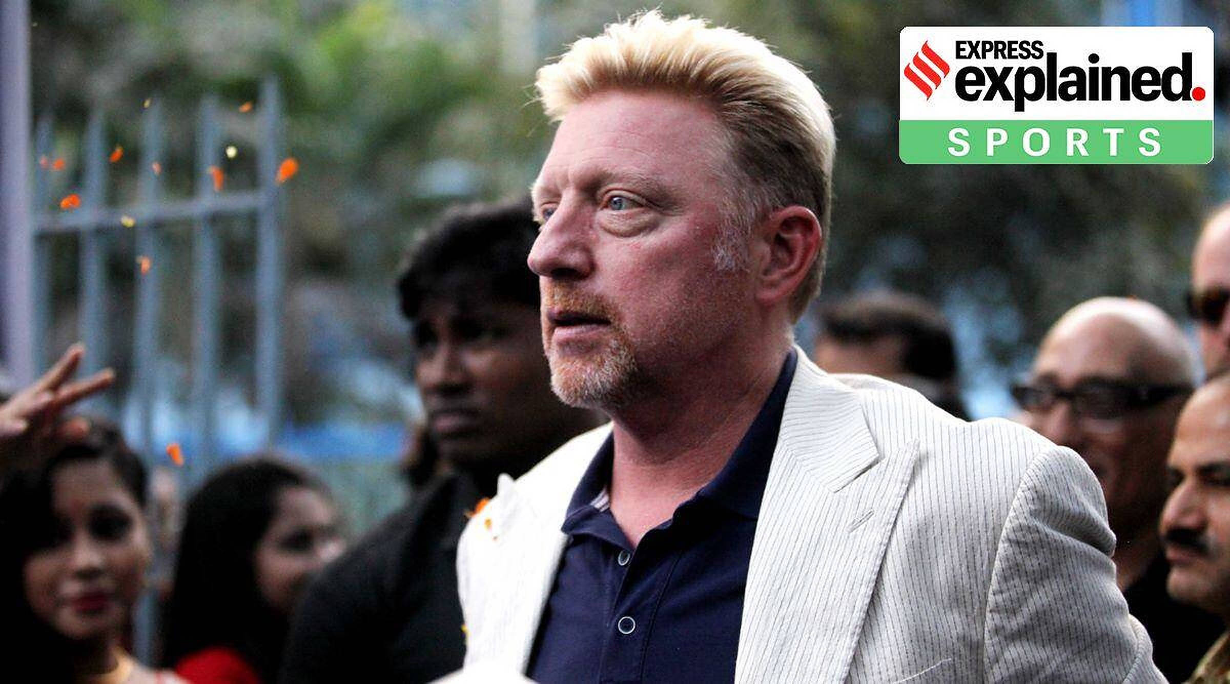 Boris Becker 桌布 壁紙 — 一位金髮男子身穿白色細條紋外套站在戶外，橙色紙屑在他周圍飄落，背景有模糊的人群。