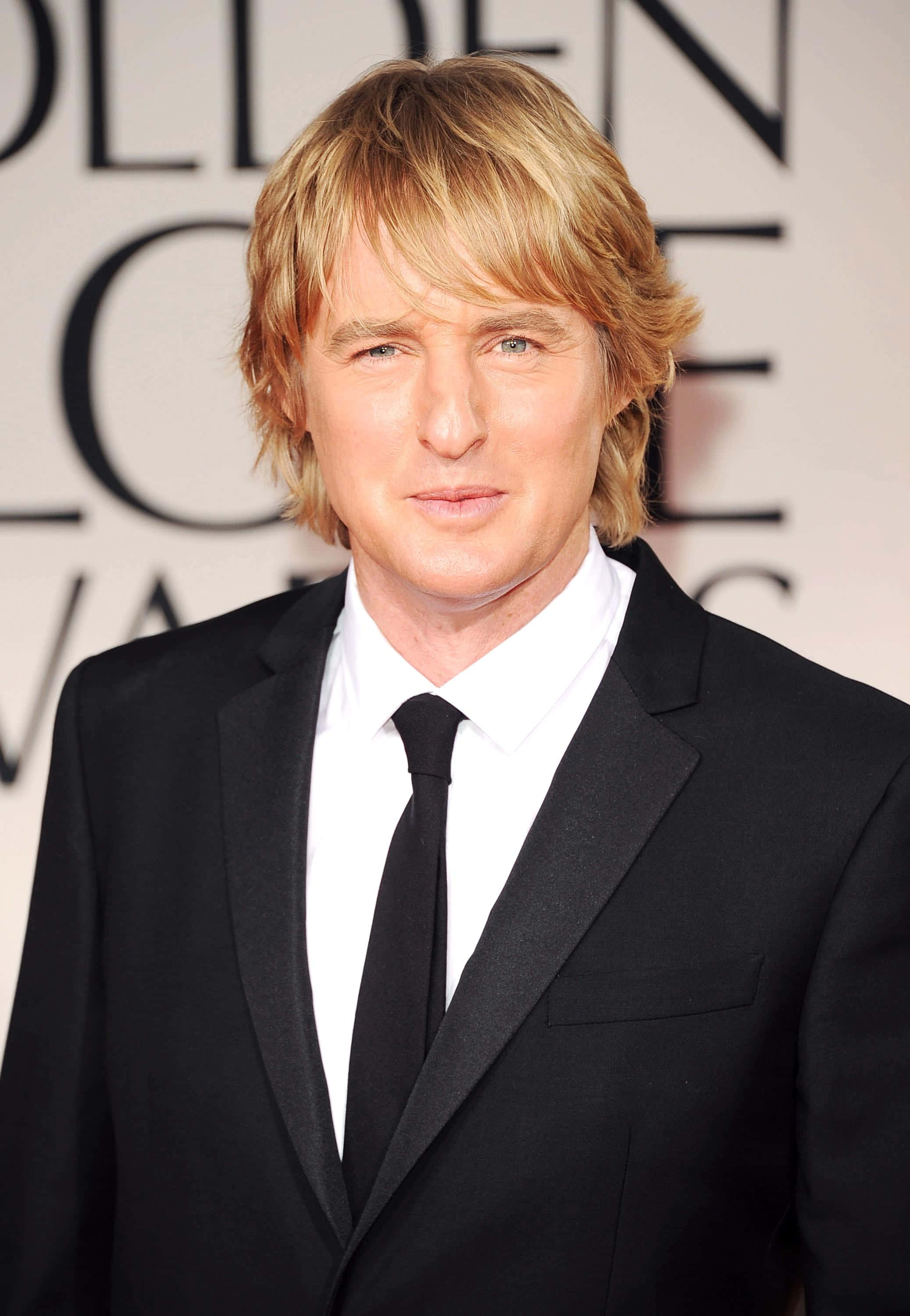 Owen Wilson 桌布 壁紙 — 一位金髮男子身穿黑色西裝打領帶，在金球獎頒獎典禮上擺姿勢。