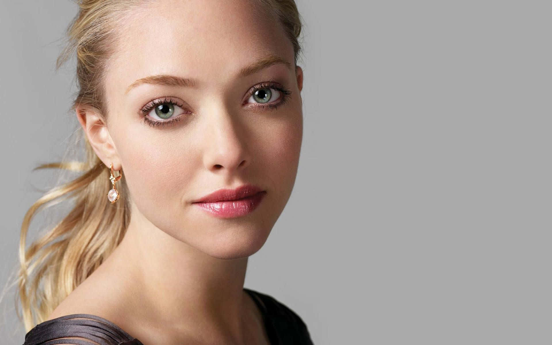 Amanda Seyfried 桌布 壁紙 — 一位金髮碧眼、戴著珍珠耳環的女性，在純灰色背景下的特寫肖像。
