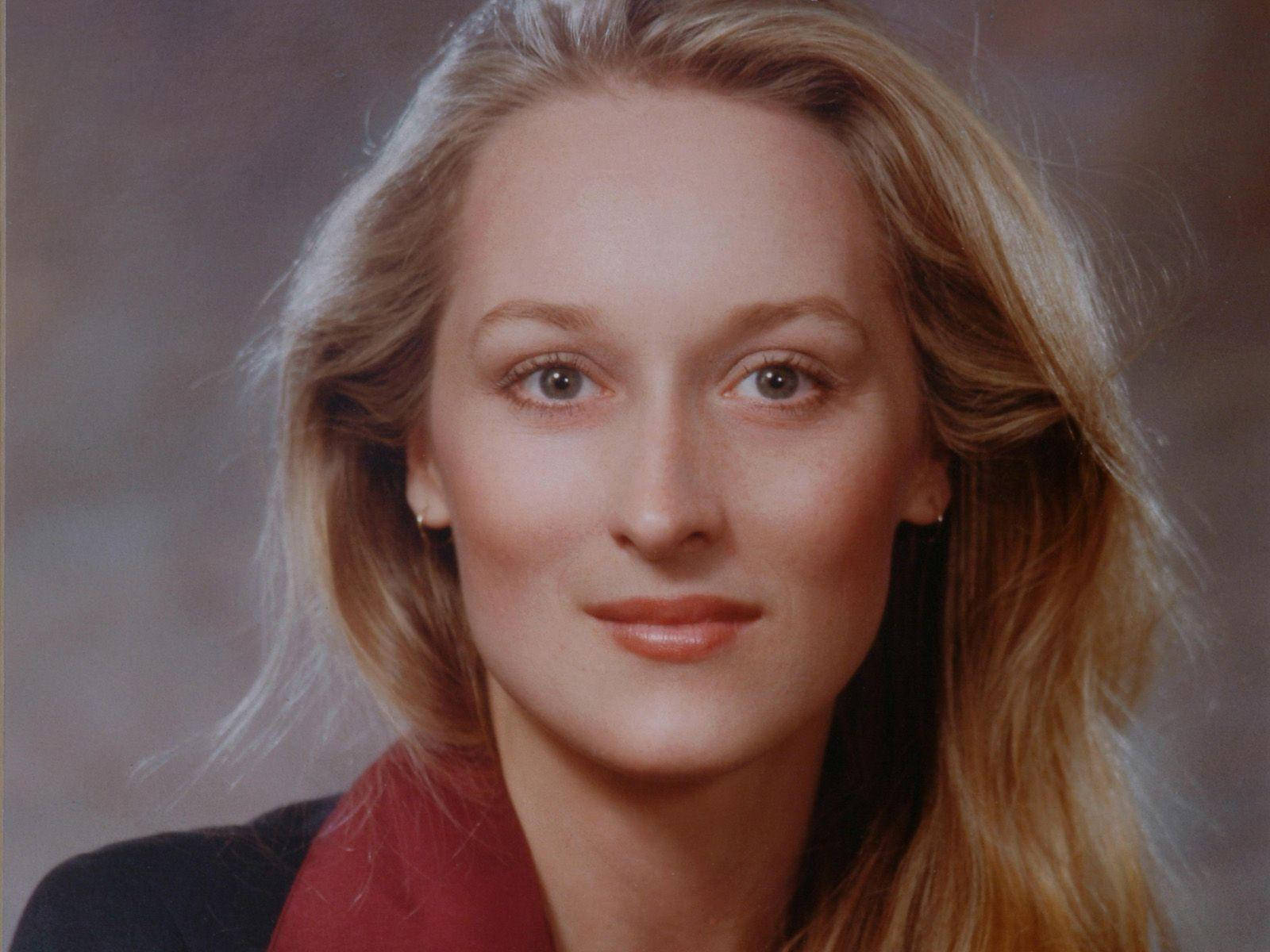 Meryl Streep 桌布 壁紙 — 一位金髮碧眼（棕色眼睛）的女性在柔和的灰色背景前微笑的特寫肖像。