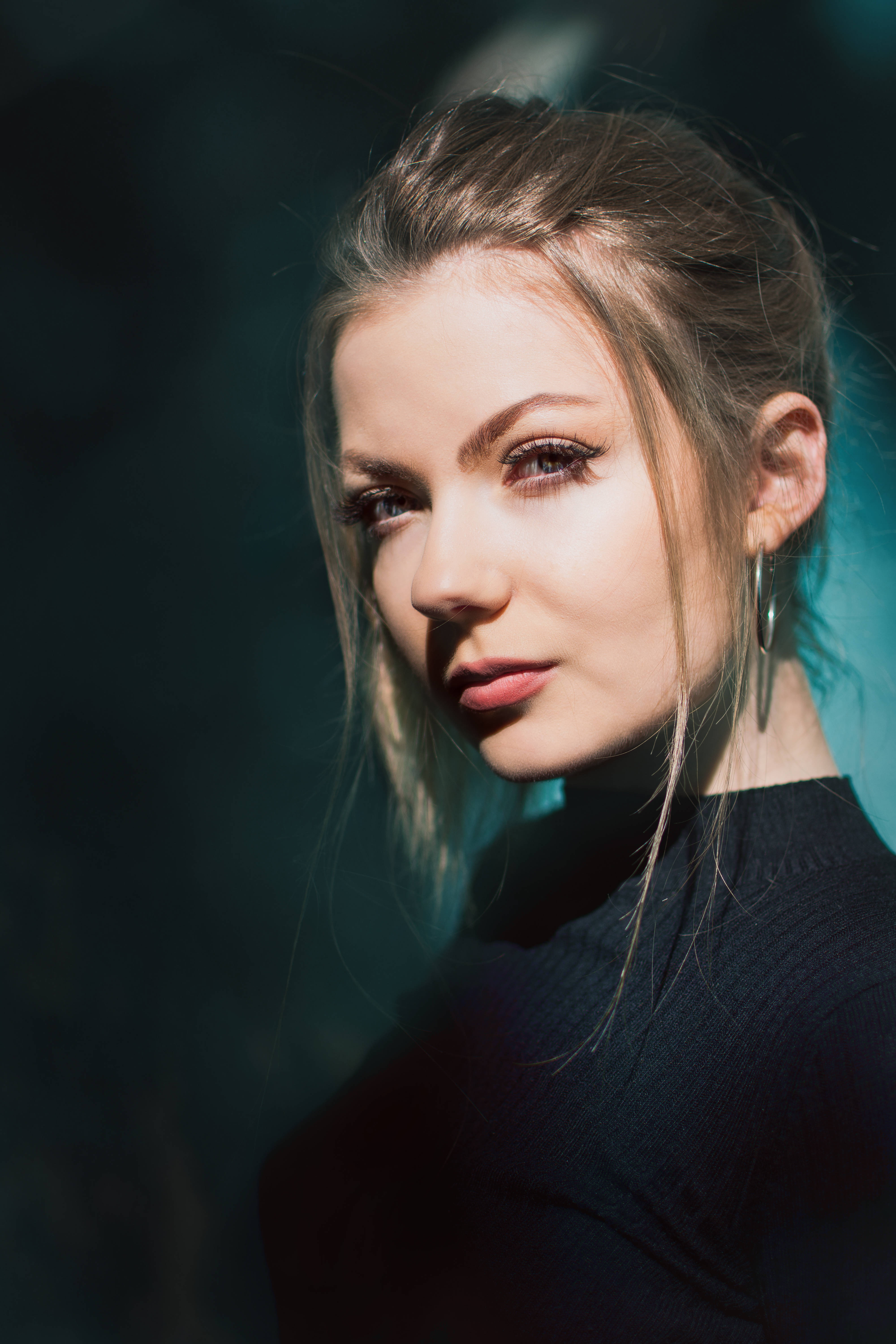 girls 桌布 壁紙 — 一位金髮碧眼、目光銳利的女性在戲劇性的藍色和黑色燈光下直視鏡頭。