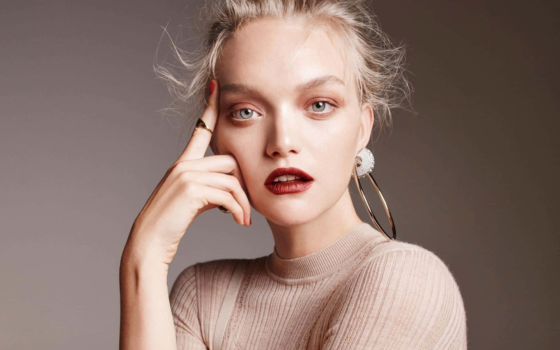 Gemma Ward 桌布 壁紙 — 一位金髮碧眼、紅唇大膽的女性在柔和的灰色背景前若有所思地擺姿勢。