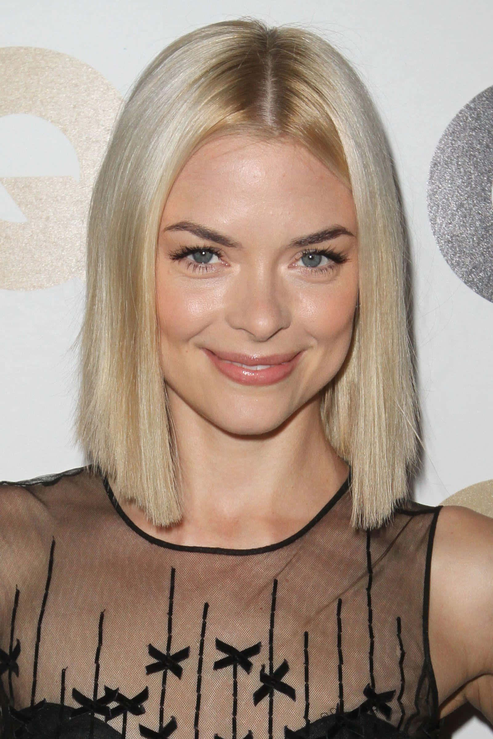 Jaime King 桌布 壁紙 — 一位金髮碧眼女士的近距離肖像，她穿著帶蝴蝶結細節的黑色薄紗上衣，對著鏡頭溫柔微笑。