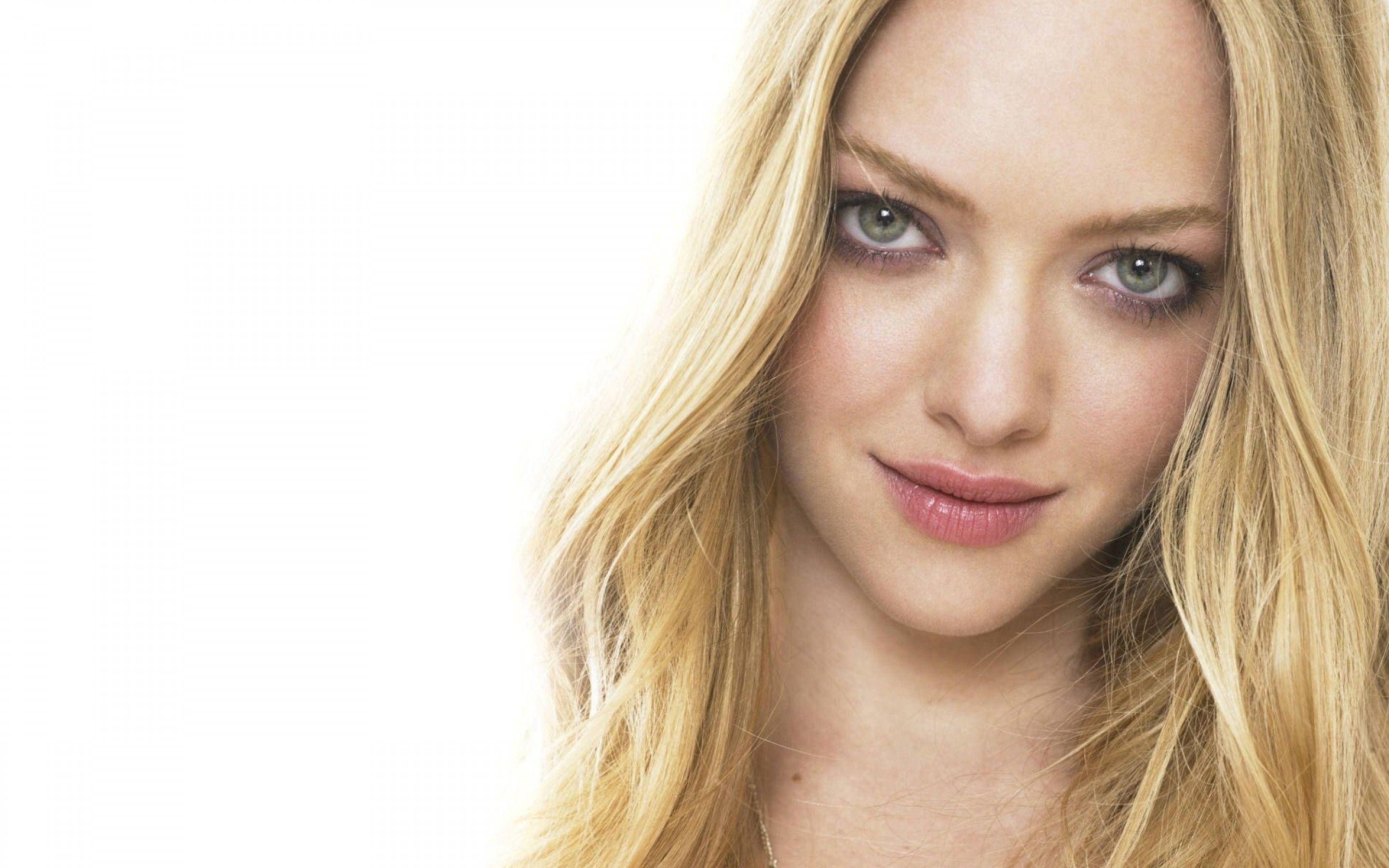 Amanda Seyfried 桌布 壁紙 — 一位金髮碧眼女子在明亮白色背景前微笑的特寫肖像。