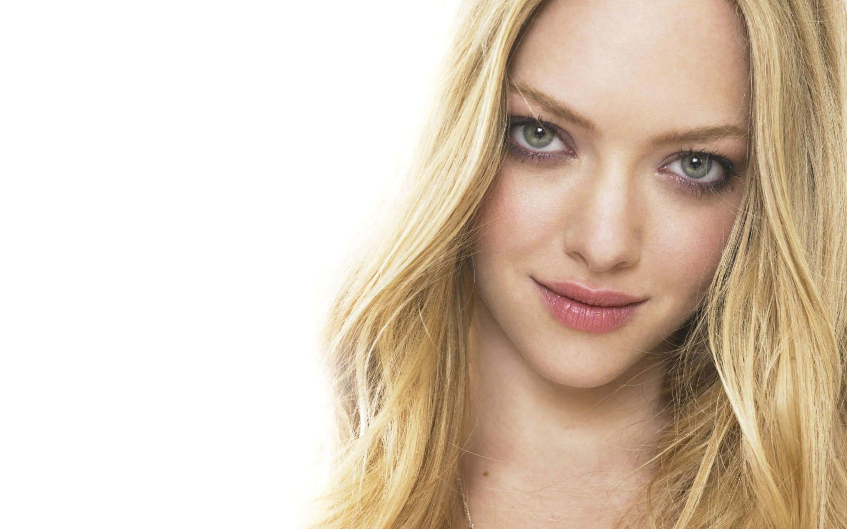 Amanda Seyfried 桌布 壁紙 — 一位金髮碧眼女子在白色背景前微笑的特寫肖像。