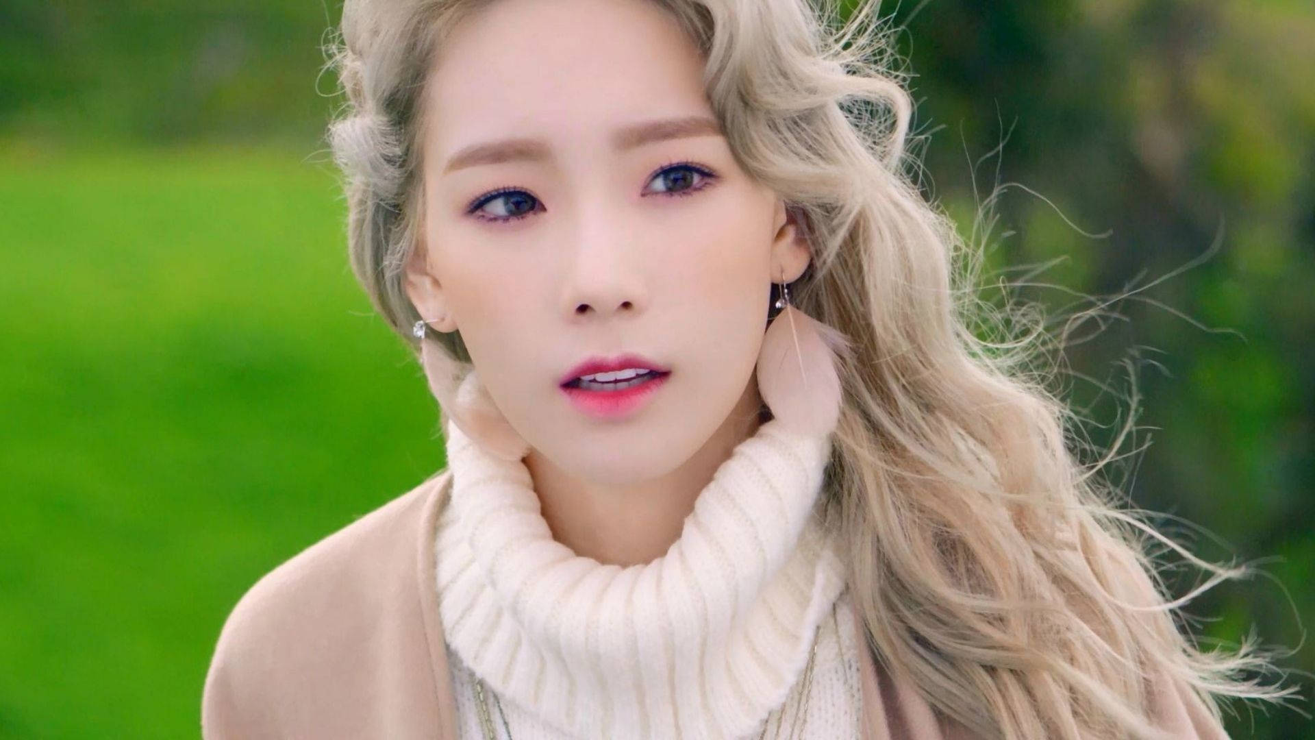 Taeyeon 桌布 壁紙 — 一位金髮碧眼的年輕女性，穿著奶油色高領毛衣和米色外套，在模糊的綠色背景下溫柔地凝視。