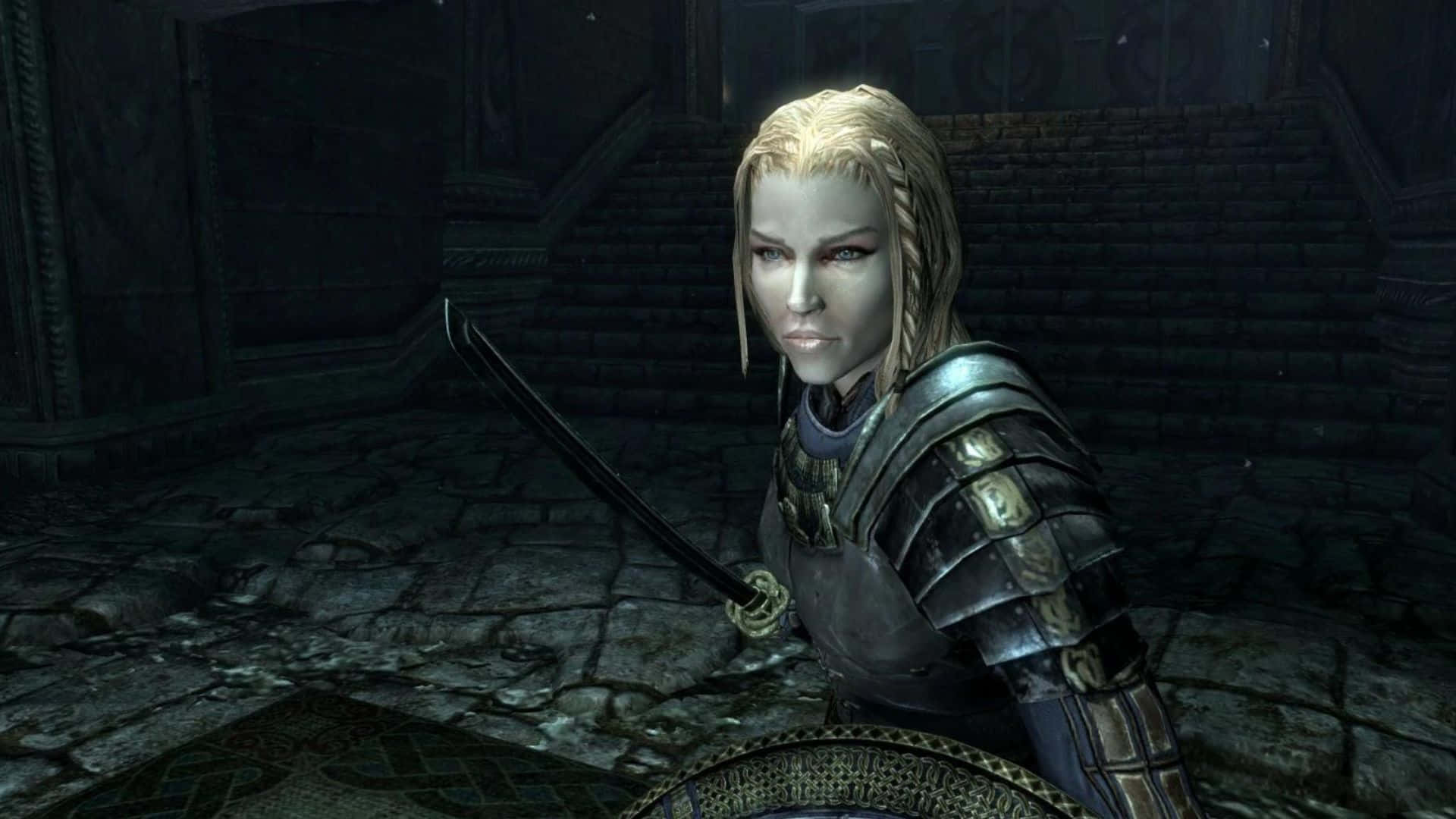 Skyrim Lydia 桌布 壁紙 — 一位金髮穿甲戰士手持劍，站在昏暗的石室中，身後有古老的樓梯。