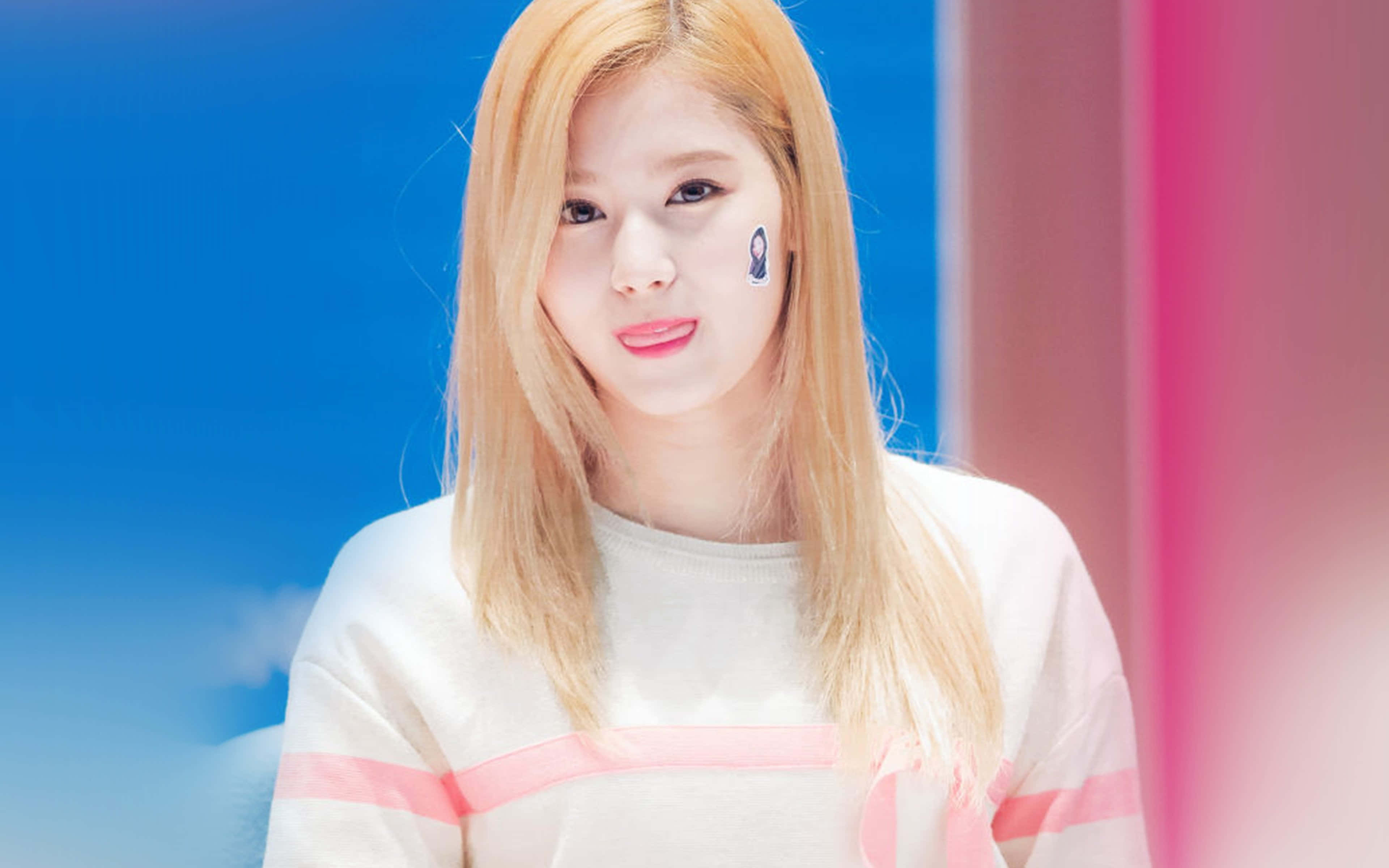 twice 桌布 壁紙 — 一位金髮粉唇的年輕女性在充滿活力的藍色和粉紅色背景下溫柔地凝視。