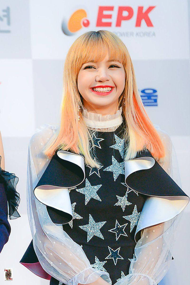 lisa 桌布 壁紙 — 一位金髮紅唇、面帶微笑的女性，在記者會上穿著帶有星星圖案的黑色連衣裙和透明荷葉邊袖。
