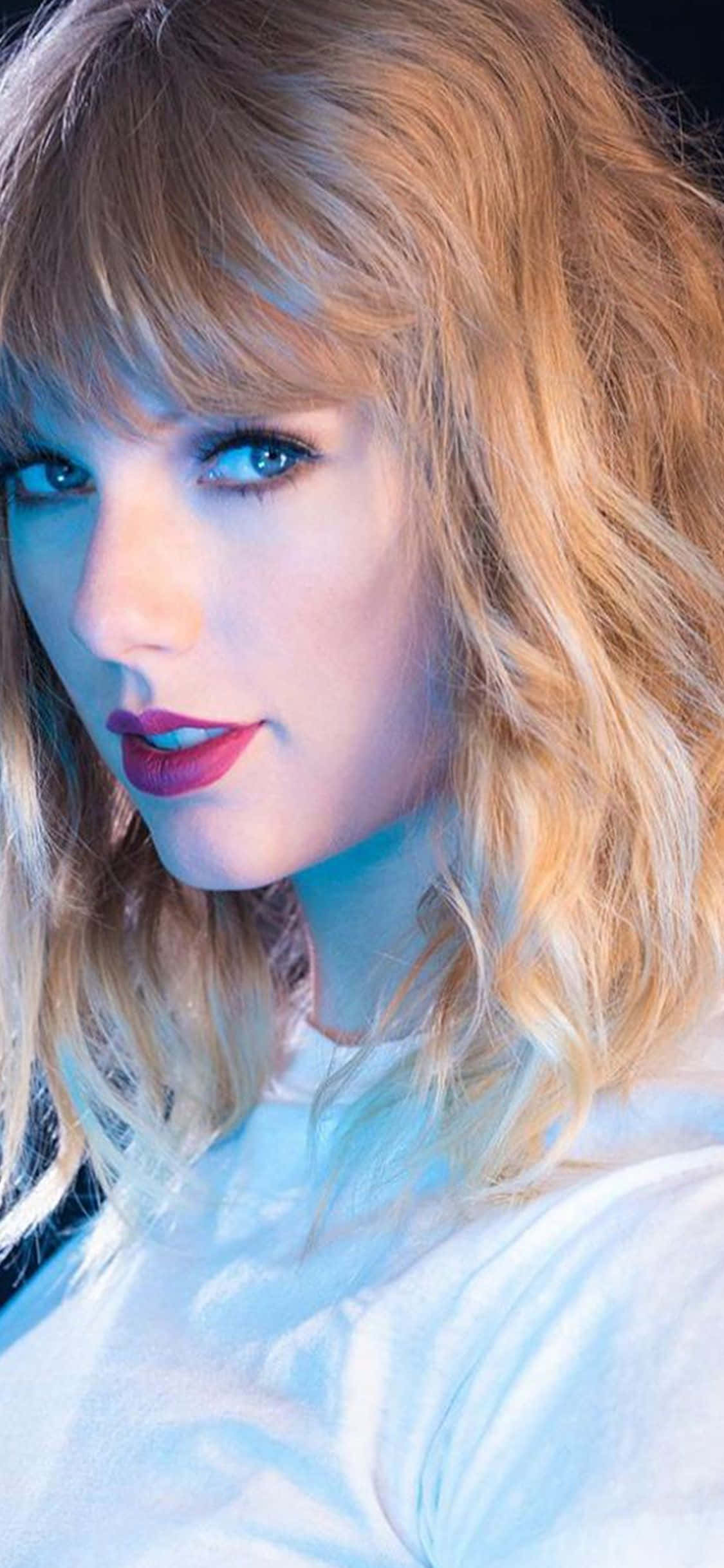 Taylor Swift iPhone 桌布 壁紙 — 一位金髮紅唇女性在冷藍色燈光下的特寫肖像。