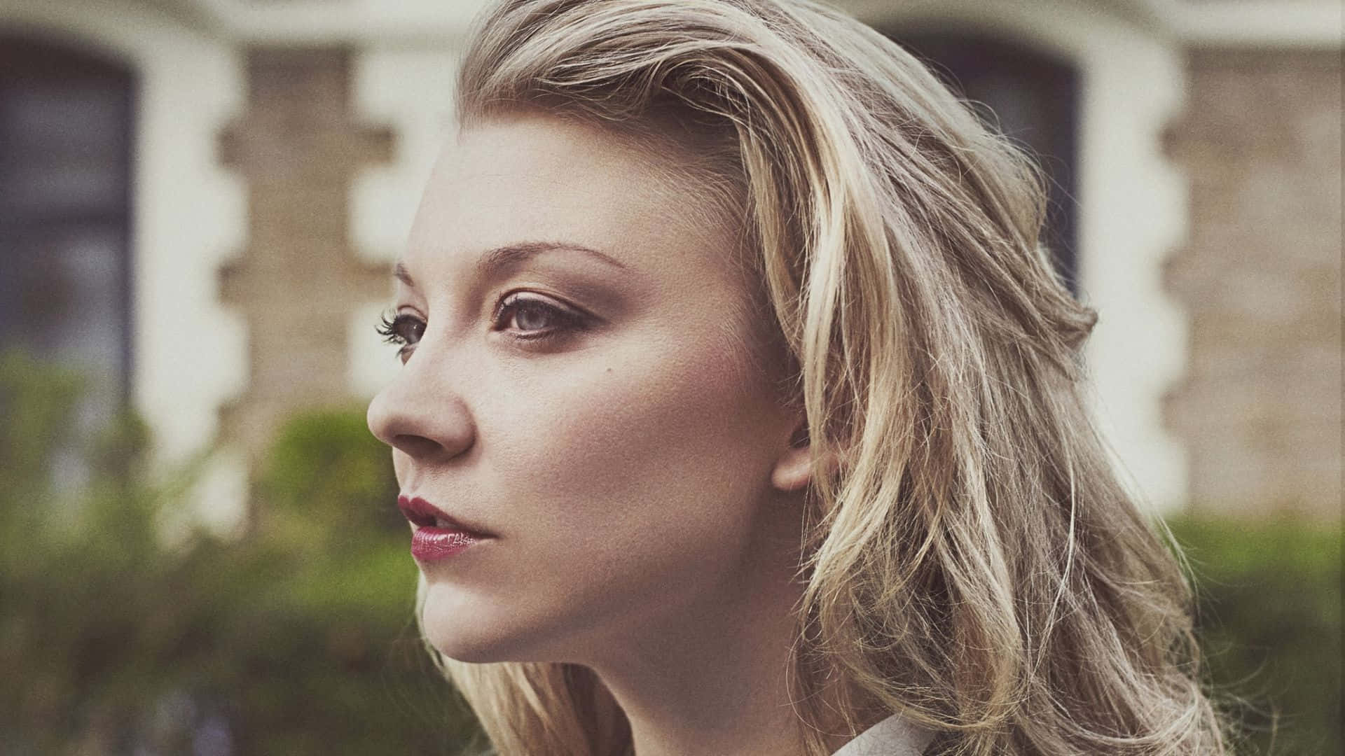 一位金髮紅唇的女性在戶外若有所思地看著。 — 娜塔莉·波曼 壁紙