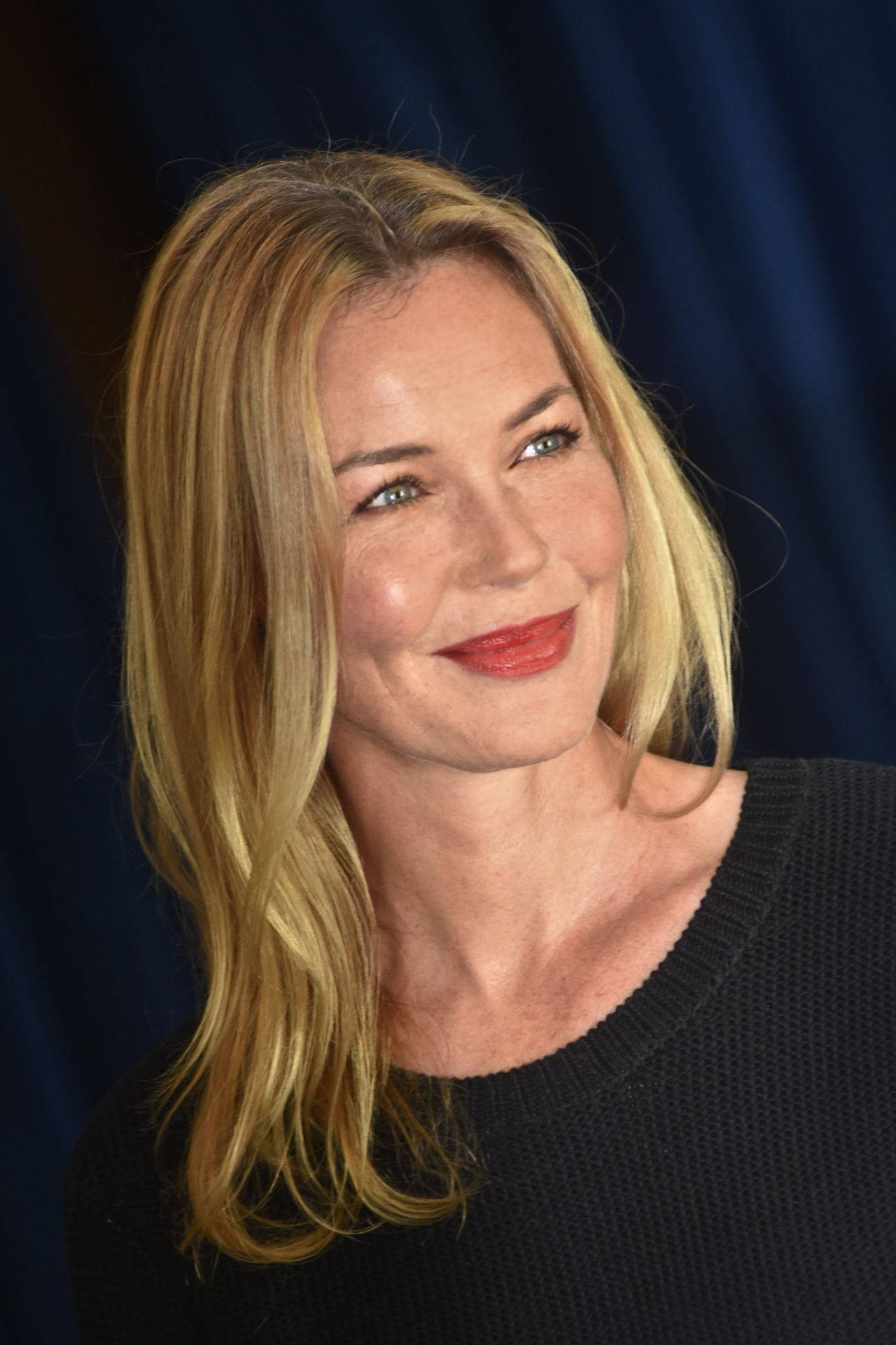 Actress HD 桌布 壁紙 — 一位金髮紅唇的女性在深藍色背景下溫暖地微笑。