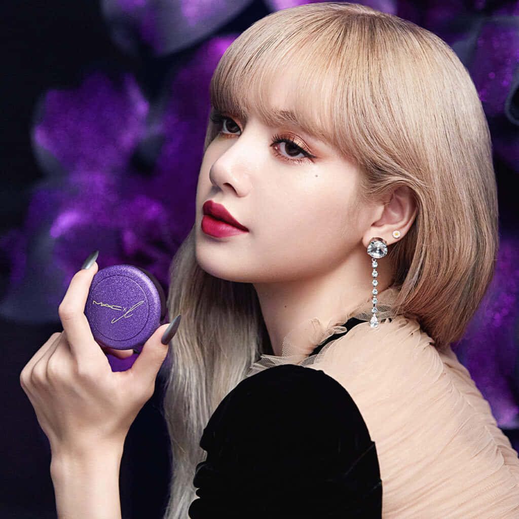 Mac Cosmetics 桌布 壁紙 — 一位金髮紅唇的女性手持紫色MAC化妝粉盒，背景是模糊的紫色花卉。