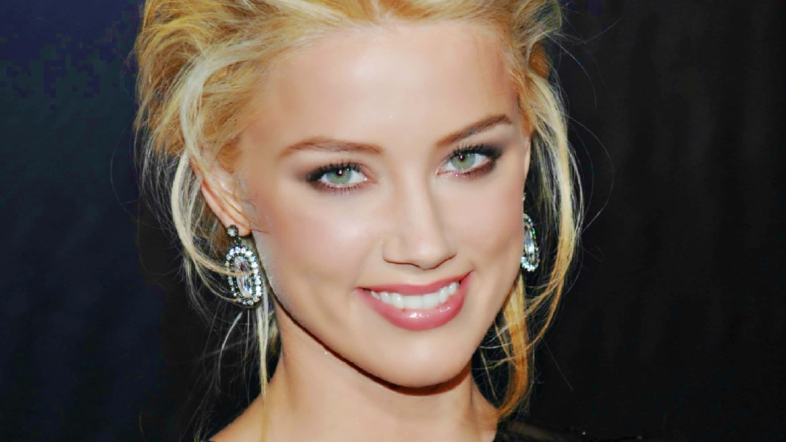 Amber Heard 桌布 壁紙 — 一位金髮綠眼的女人在深色背景下溫暖微笑的特寫肖像。