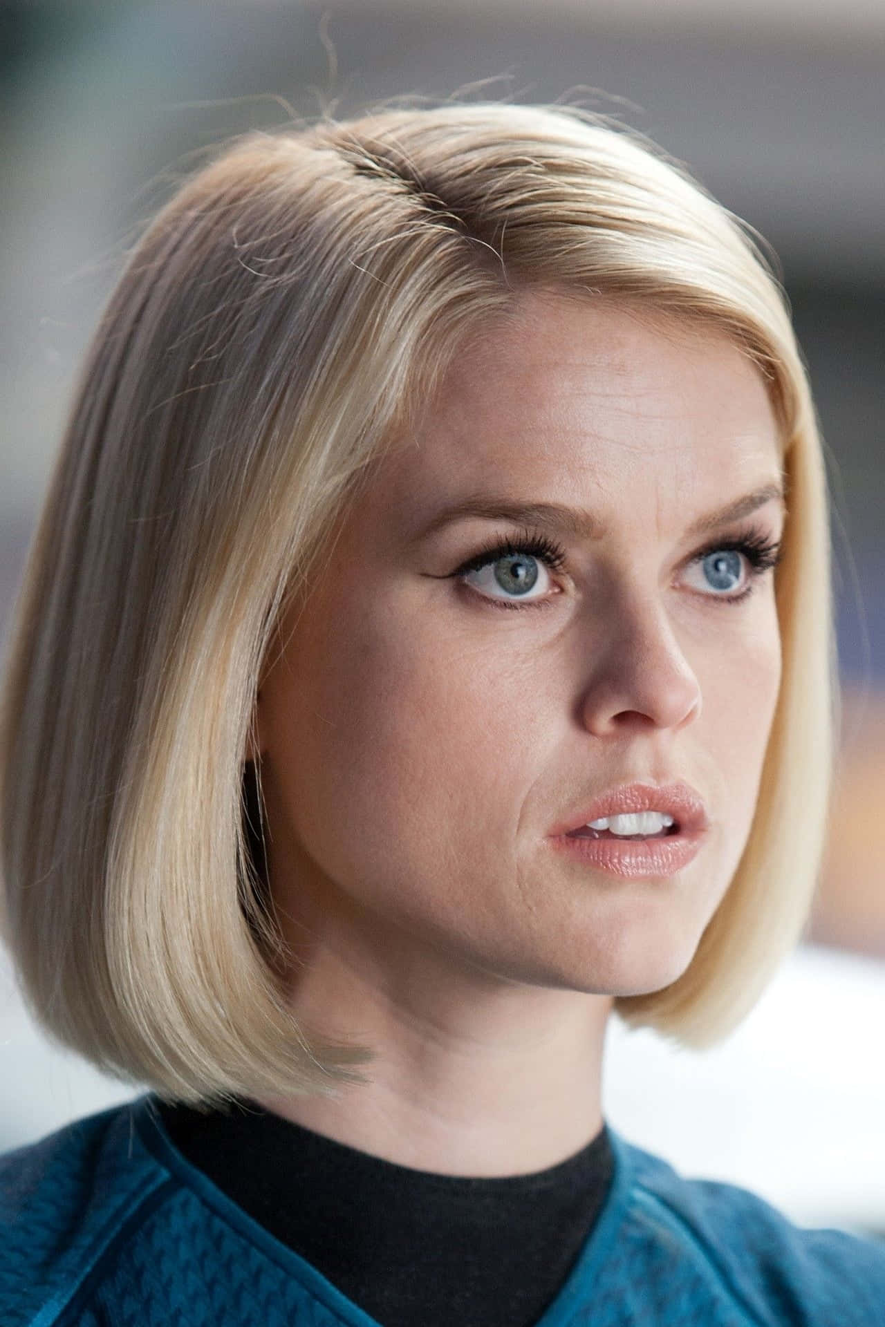 alice eve 桌布 壁紙 — 一位金髮藍眼、表情憂慮的女性穿著青綠色制服的特寫肖像。