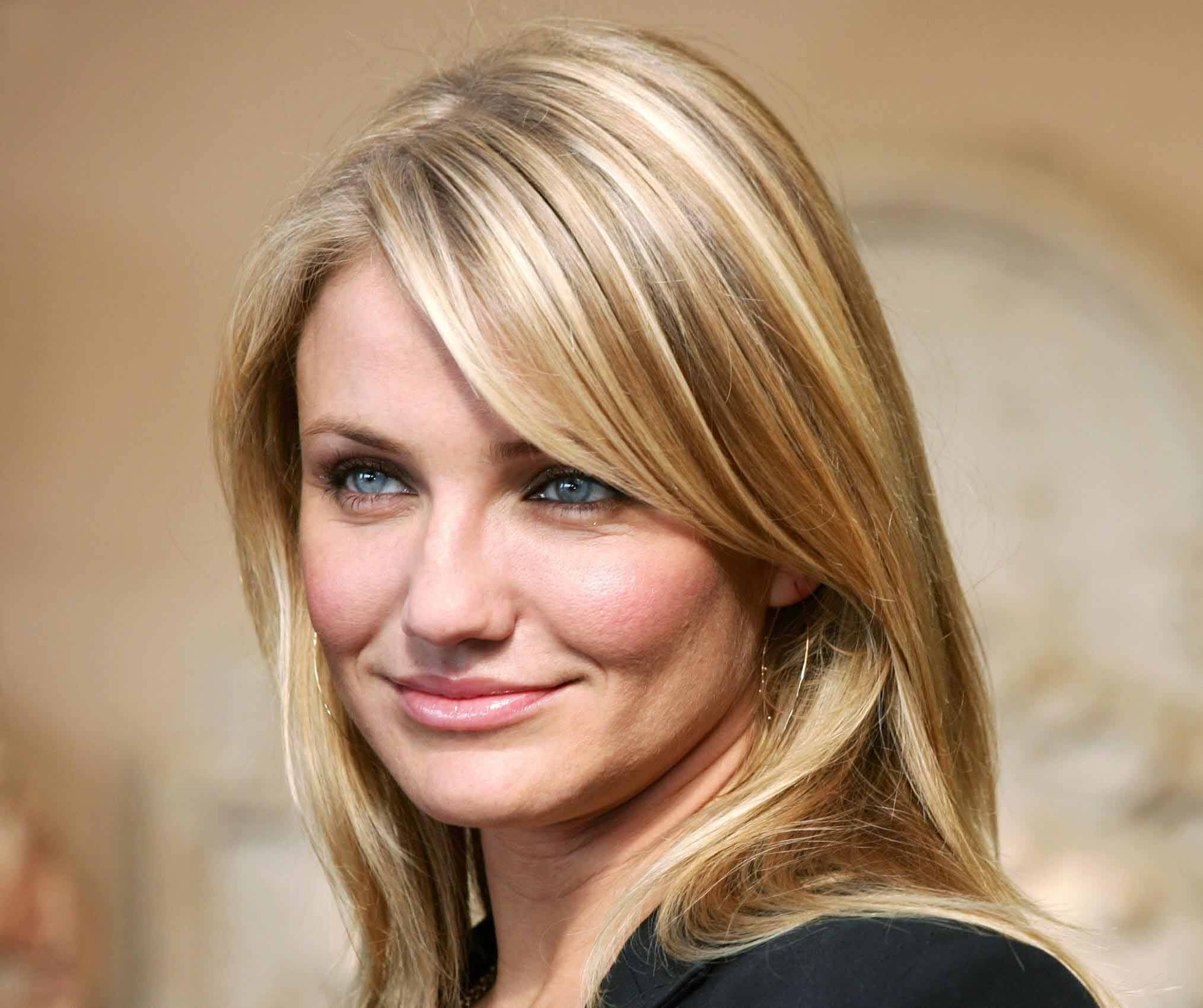 Celebrity 桌布 壁紙 — 一位金髮藍眼女士在溫暖模糊背景前輕柔微笑的特寫肖像。