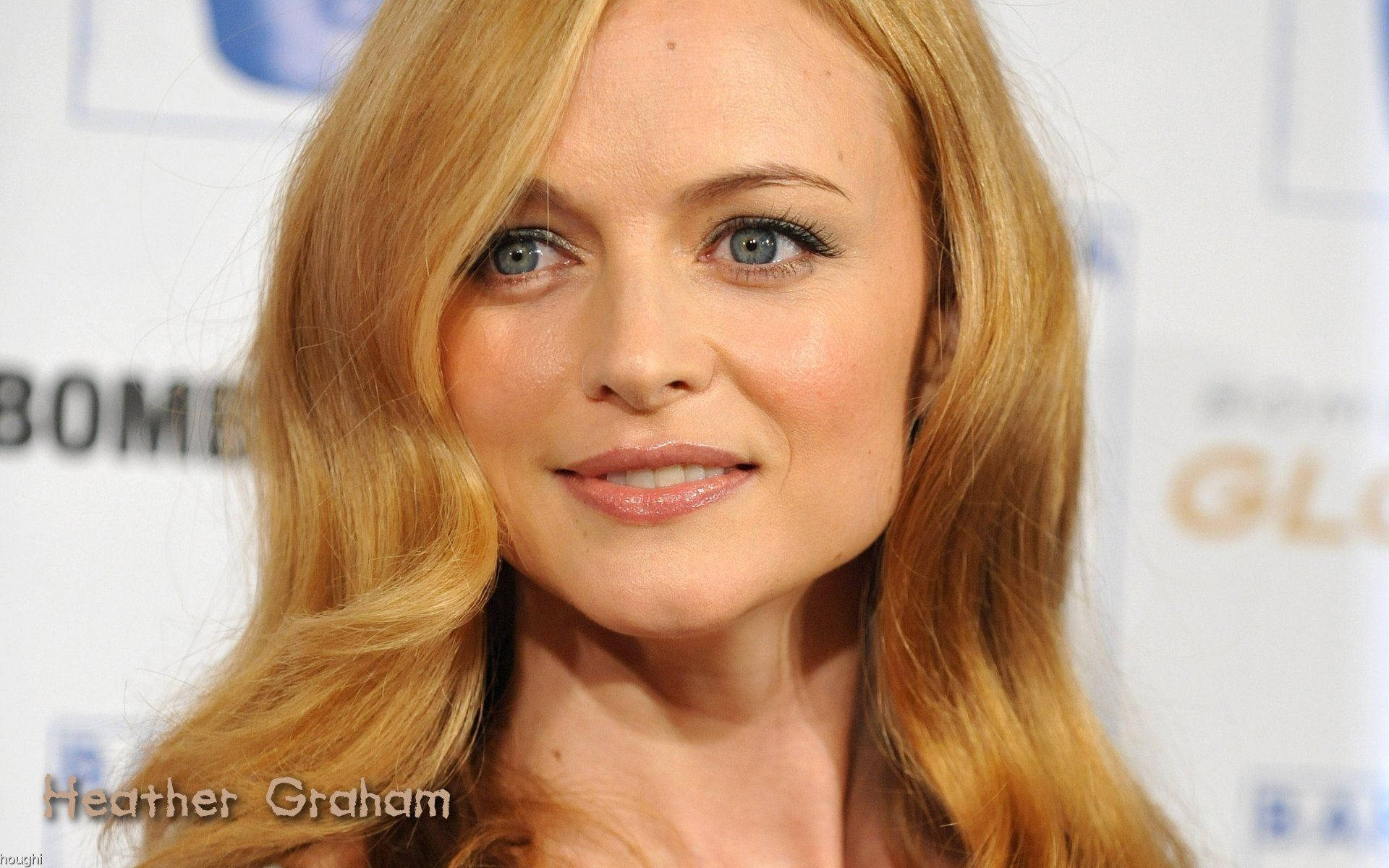 Heather Graham 桌布 壁紙 — 一位金髮藍眼女士的近距離肖像，溫柔地對著鏡頭微笑。