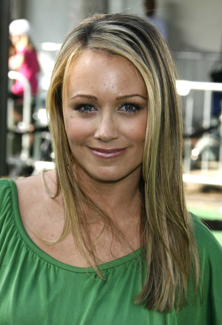 Christine Taylor 桌布 壁紙 — 一位金髮藍眼女士身穿綠色上衣，對著鏡頭溫柔微笑的特寫肖像。