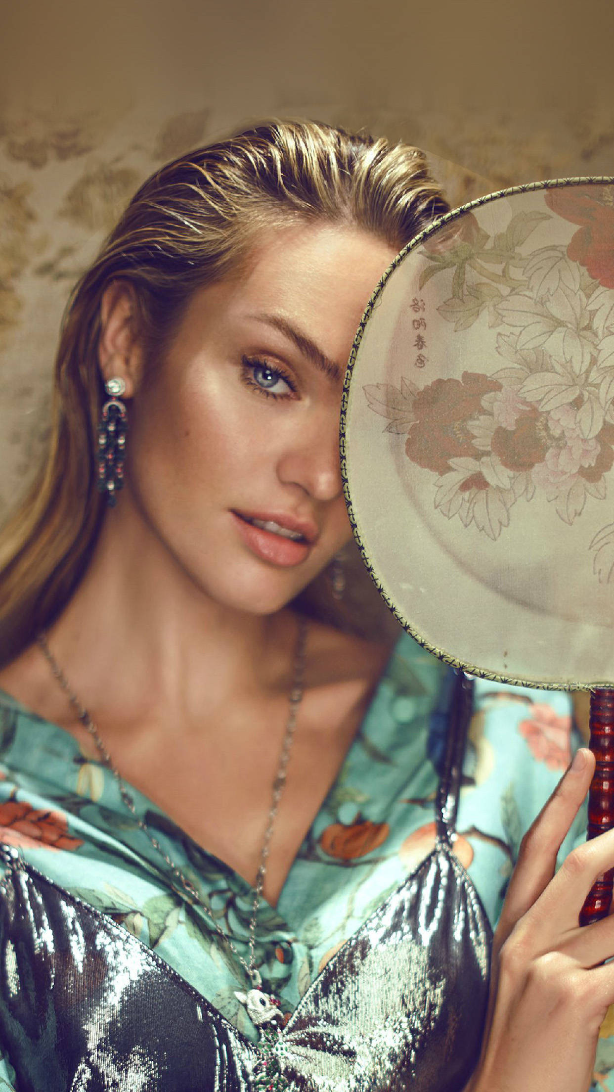 Candice 桌布 壁紙 — 一位金髮藍眼女子手持花卉扇子半遮臉，背景為圖案壁紙。