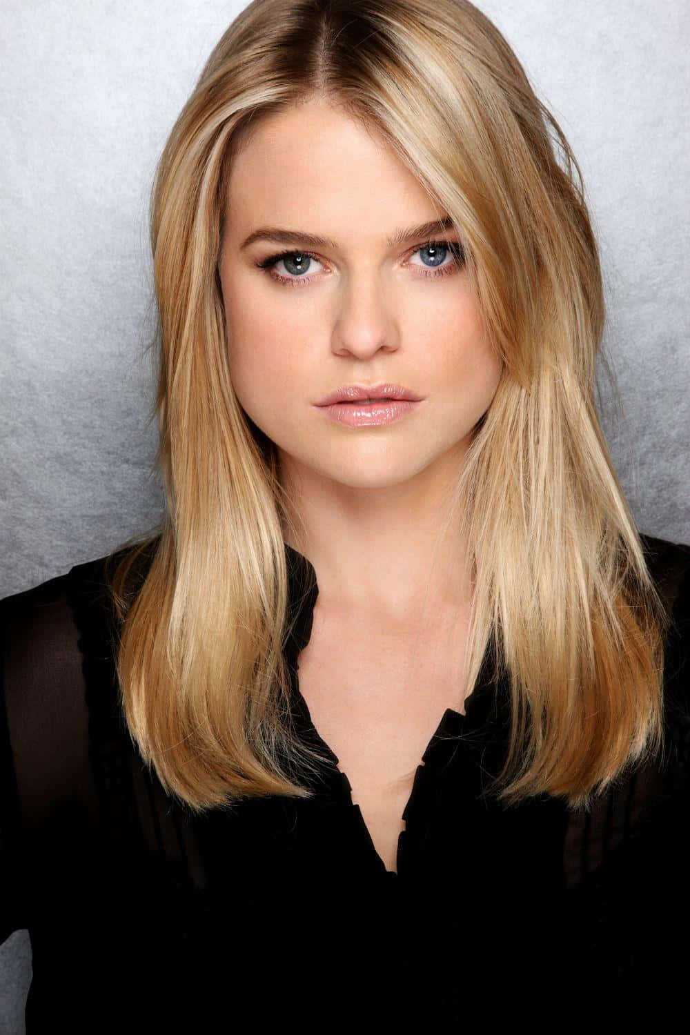 alice eve 桌布 壁紙 — 一位金髮藍眼女性穿著黑色上衣，在灰色紋理背景前的特寫肖像。