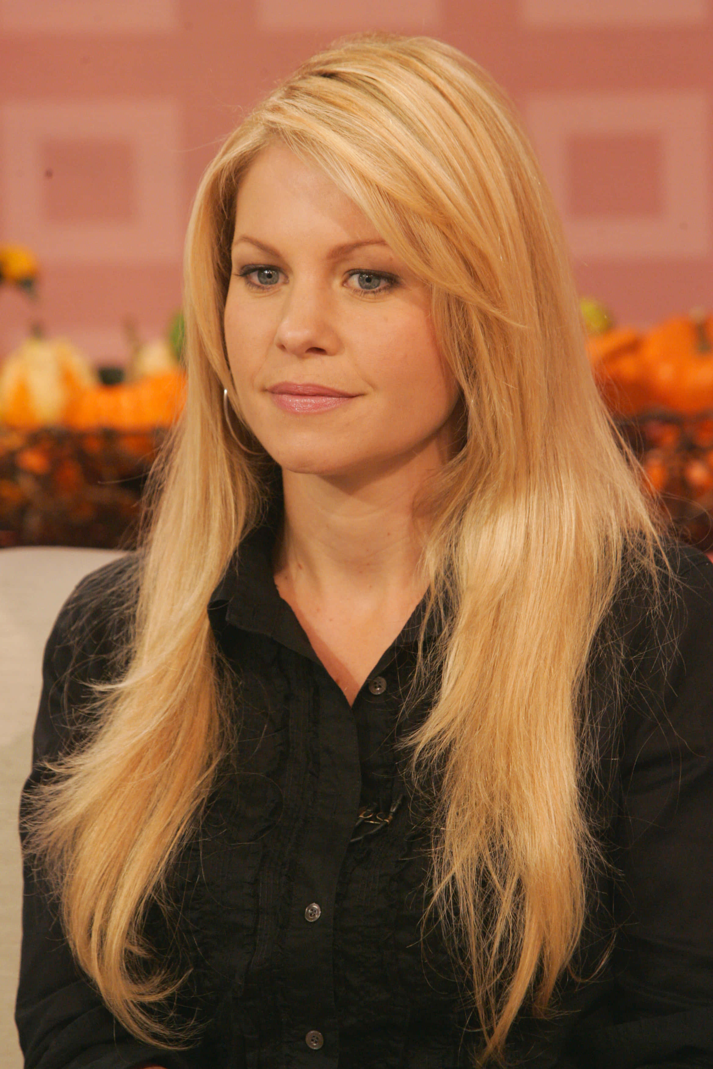 candace cameron bure 桌布 壁紙 — 一位金髮長髮女性冷靜地坐在南瓜和秋季裝飾的背景前。