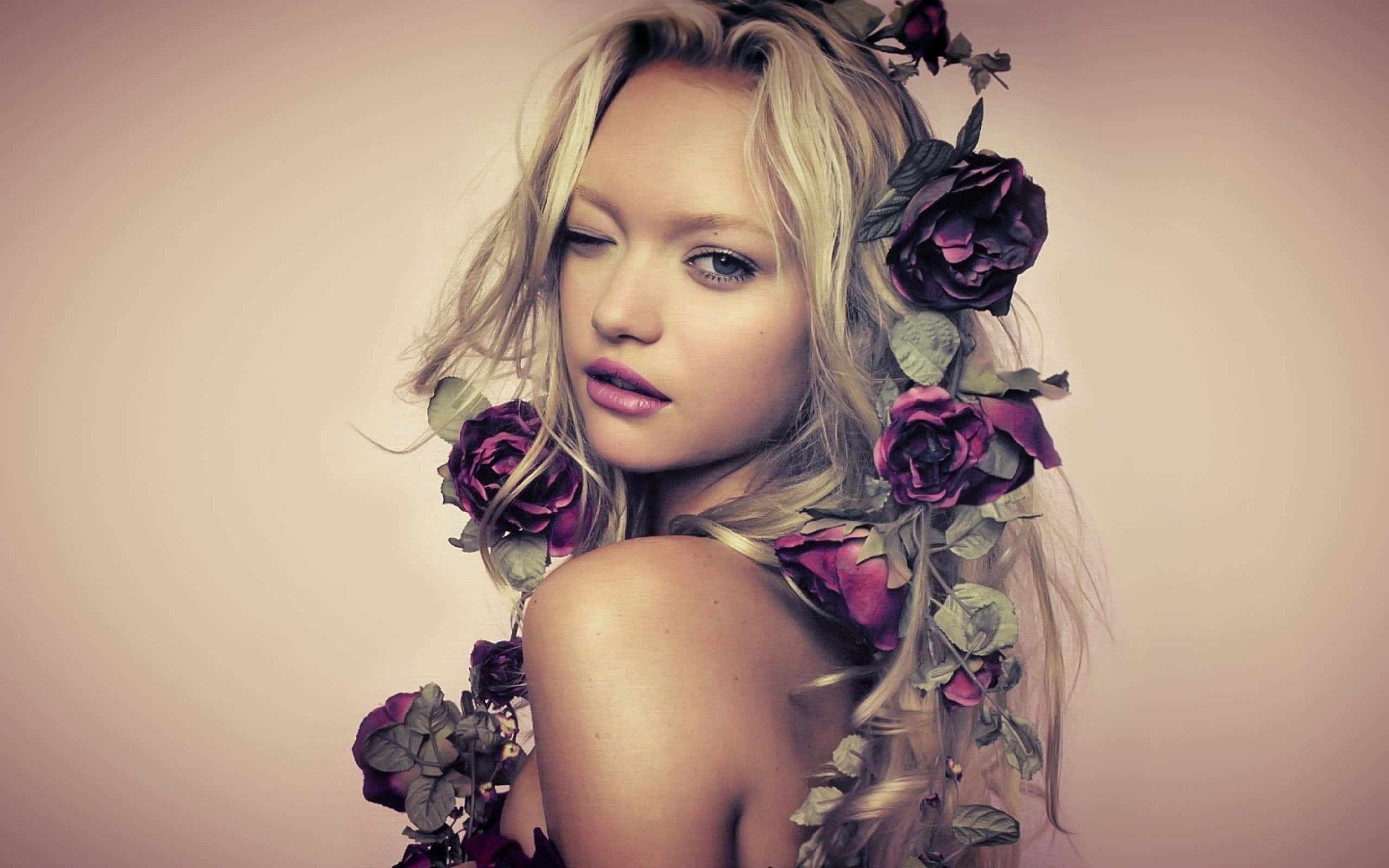 Gemma Ward 桌布 壁紙 — 一位金髮閉眼女子，深紫色玫瑰編織在她的頭髮中，背景是柔和的粉紅色。