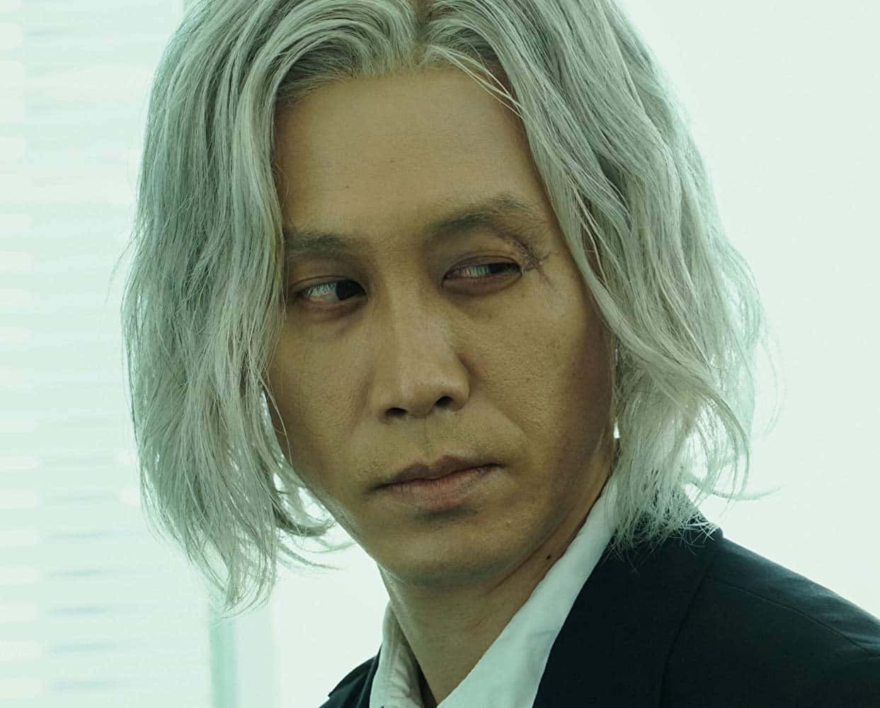 Tokyo Ghoul Movie 桌布 壁紙 — 一位銀髮、表情嚴肅的男子，穿著黑色西裝，背景是明亮的窗戶。