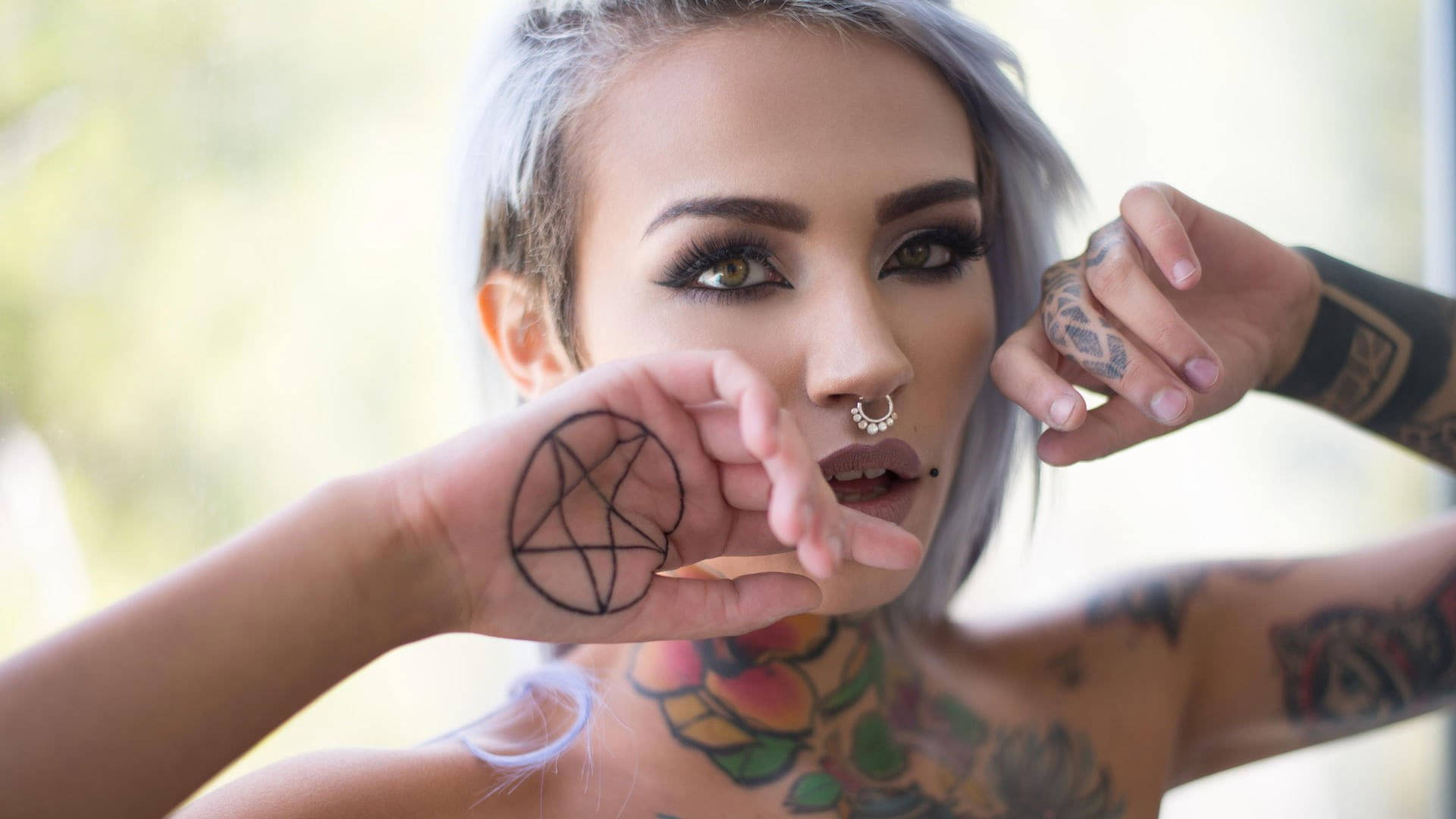 Tattoo 桌布 壁紙 — 一位銀髮且帶有刺青的女性舉起手展示五角星符號，同時專注地凝視鏡頭。