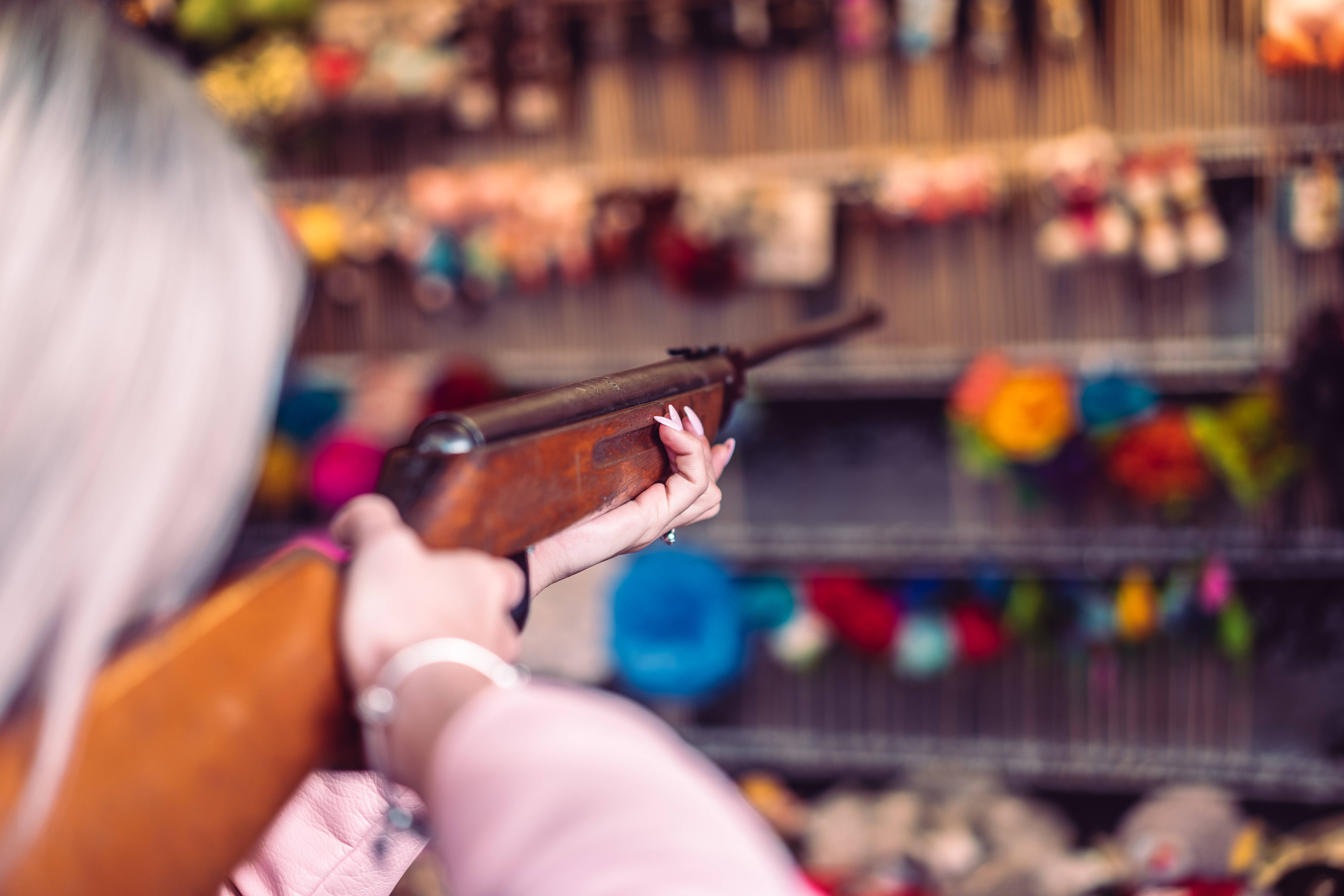 Shooting 桌布 壁紙 — 一位銀髮人士在色彩繽紛的玩具店中手持一把復古木製步槍，身後是模糊的貨架。