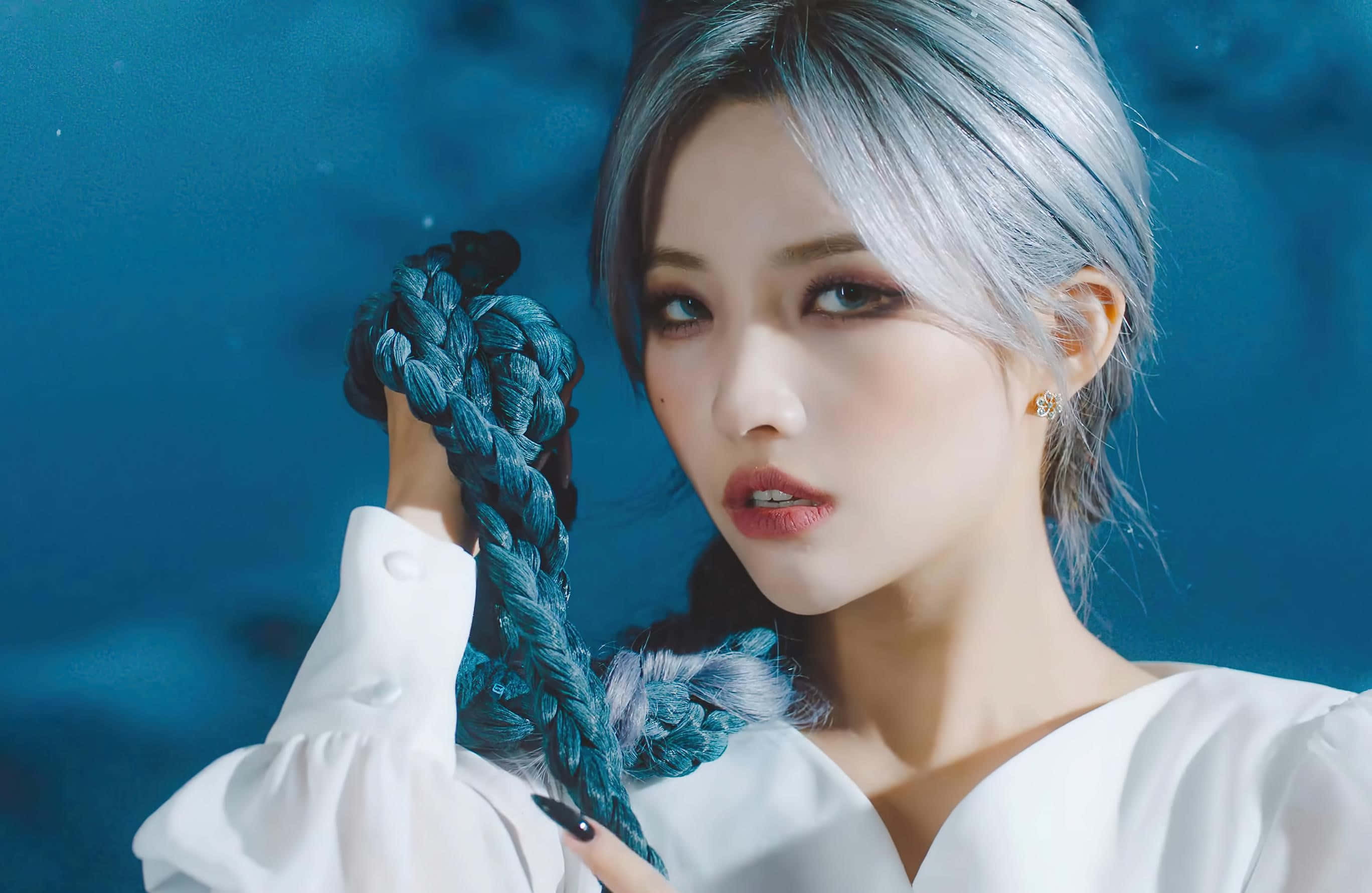 K-pop 桌布 壁紙 — 一位銀髮女性在深藍色背景前拿著一條青綠色的編織繩。