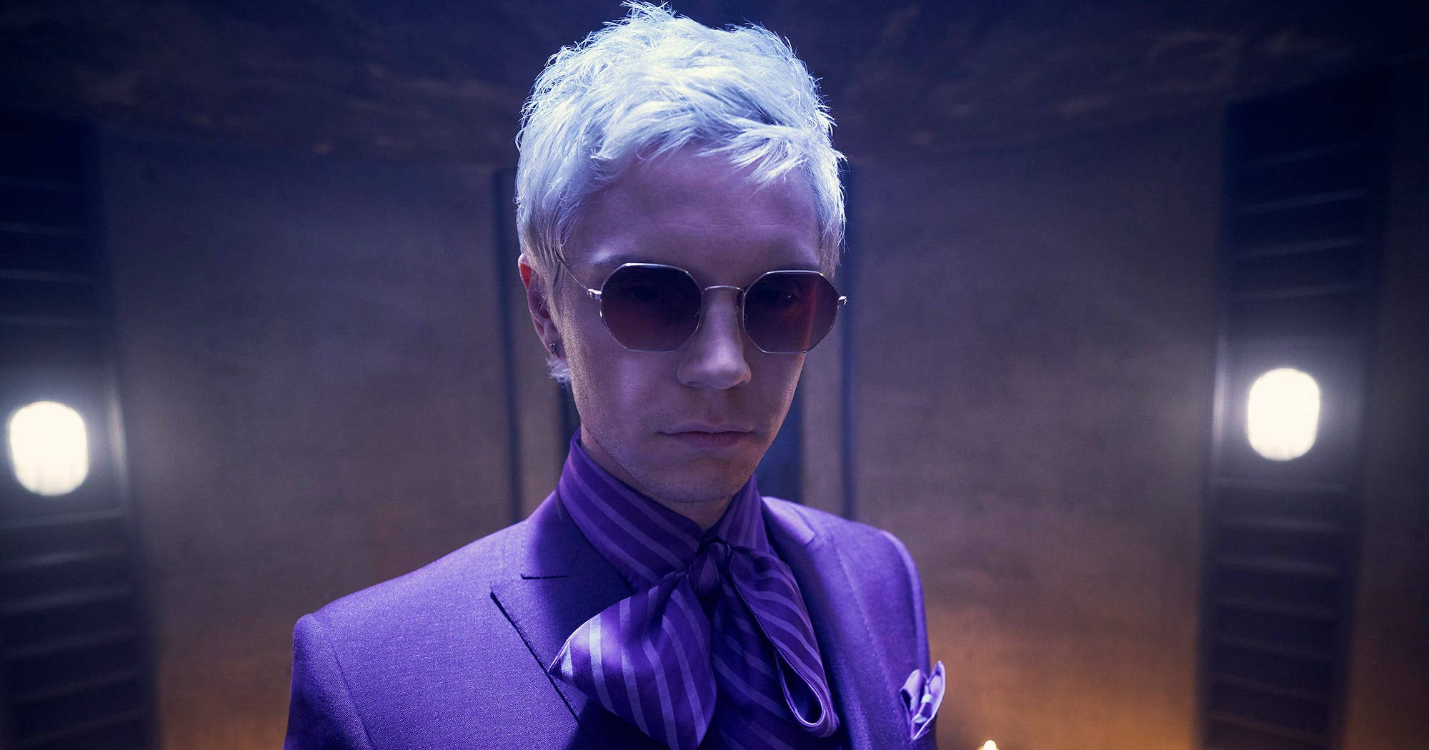 Tate Langdon 桌布 壁紙 — 一位銀髮戴太陽眼鏡的男子，在戲劇性的工作室燈光下穿著鋒利的紫色西裝。