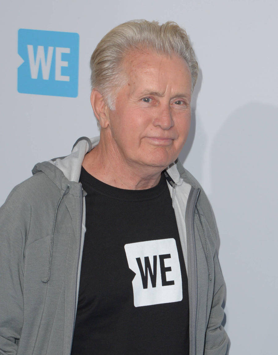 actor 桌布 壁紙 — 一位銀髮老男人穿著灰色連帽衫，內搭黑色T恤，兩件衣服上都有白色方形標誌，上面有粗體黑色的WE字母。