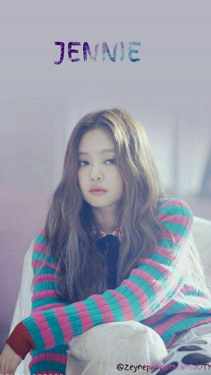 Jennie 桌布 壁紙 — 一位長捲髮的年輕女性穿著色彩繽紛的條紋毛衣，以柔和的表情直視鏡頭。