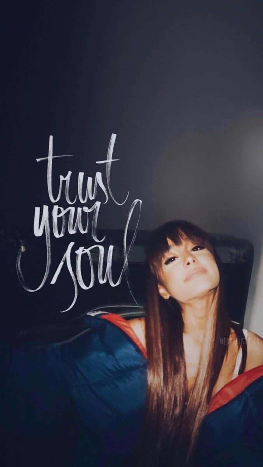 Aesthetic Ariana Grande 桌布 壁紙 — 一位長棕色頭髮的女性在深色背景上，優雅的白色草書文字「trust your soul」旁邊向上凝視。