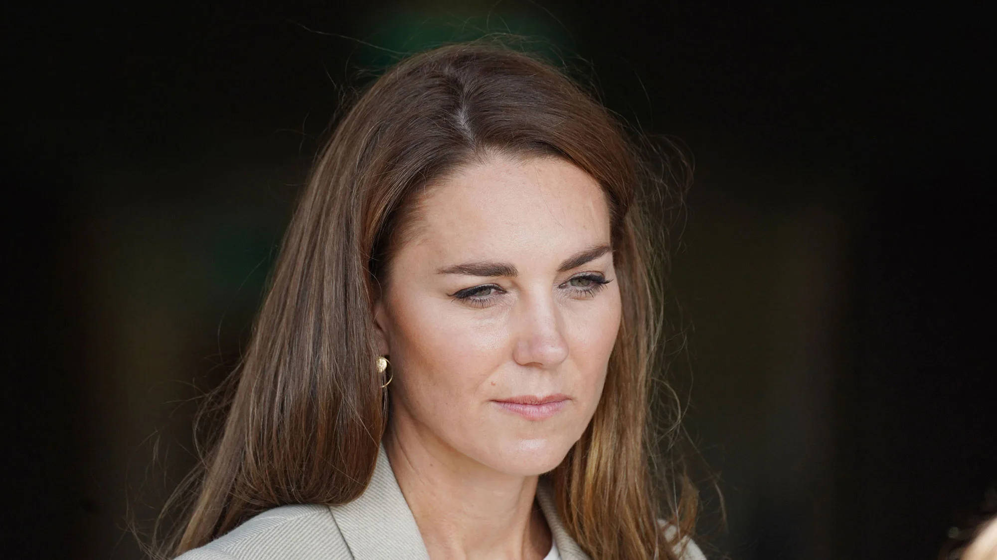 Kate Middleton 桌布 壁紙 — 一位長棕髮、表情中性的女性穿著米色西裝外套的特寫肖像。