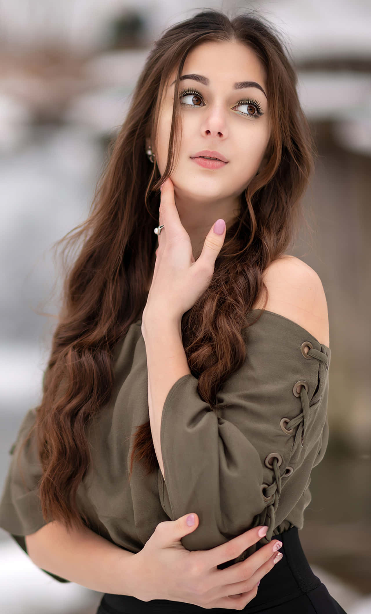 Cute Girl 桌布 壁紙 — 一位長棕髮的年輕女性在雪地戶外環境中向上凝視，身穿橄欖色露肩上衣。
