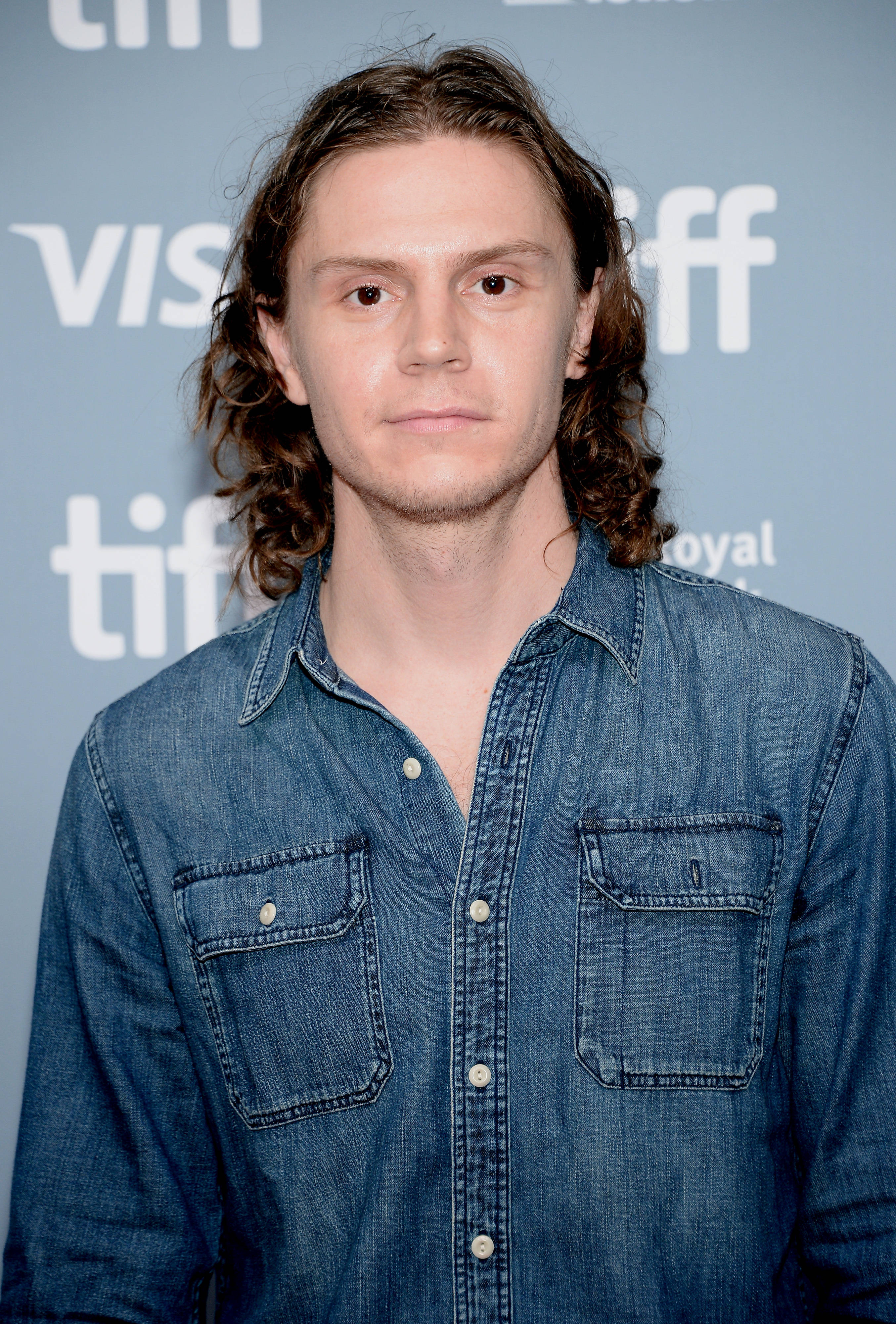 Tate Langdon 桌布 壁紙 — 一位長波浪棕色頭髮的年輕男子穿著牛仔襯衫，背景是藍色TIFF。